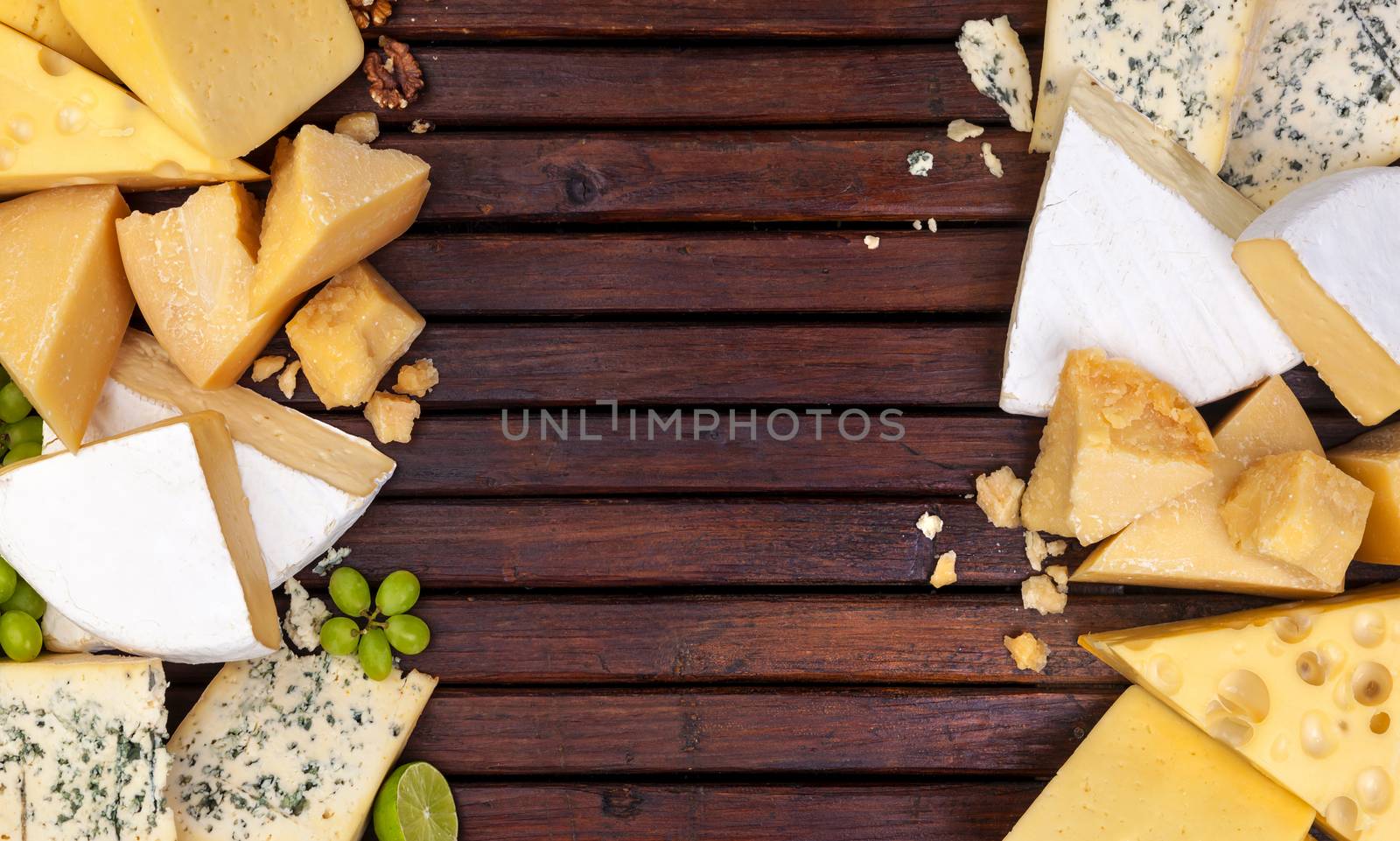 Various types of cheese on wooden table background. Cheddar, parmesan, emmental, blu cheese. Top view, copy space.