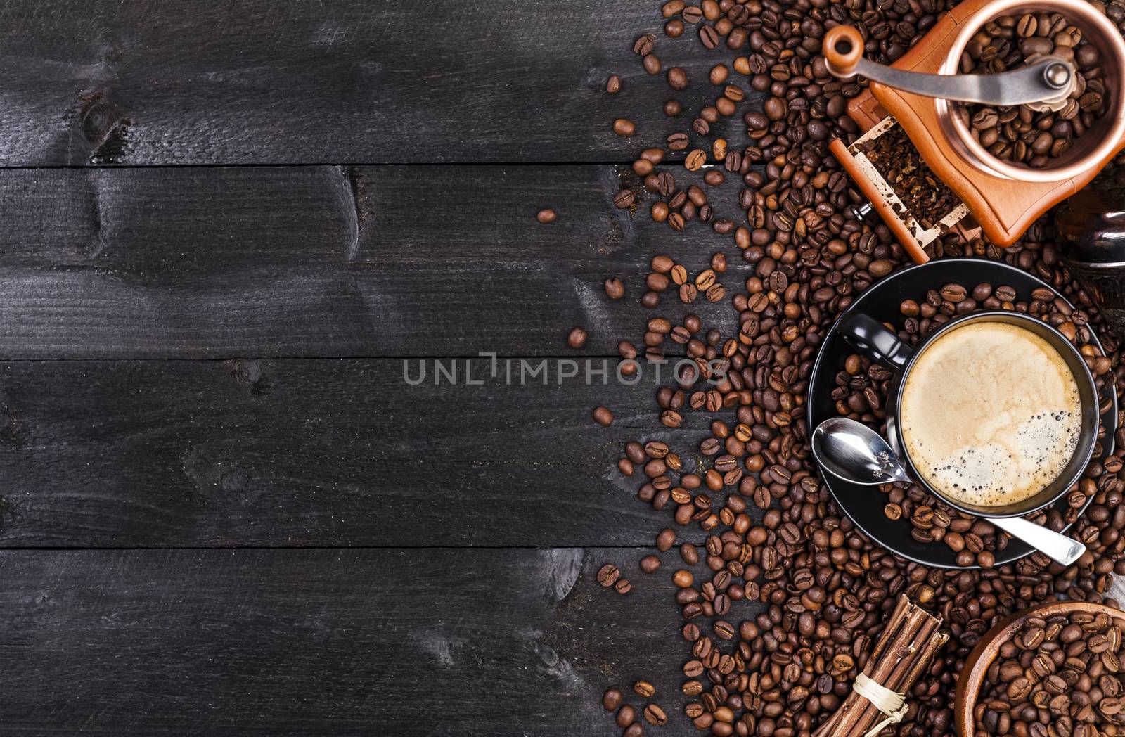 Coffee background, top view with copy space. Black cup of coffee, ground coffee, mill, bowl of roasted coffee beans on dark wooden background