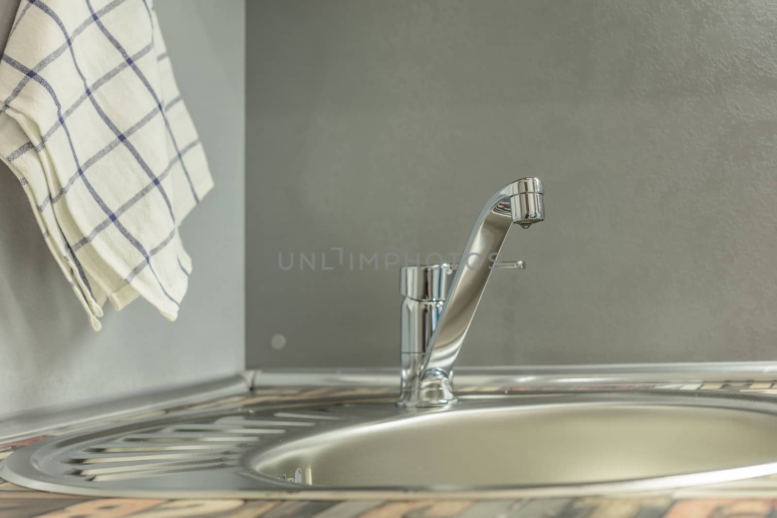 Close up of modern faucet and ceramic sink in kitchen
