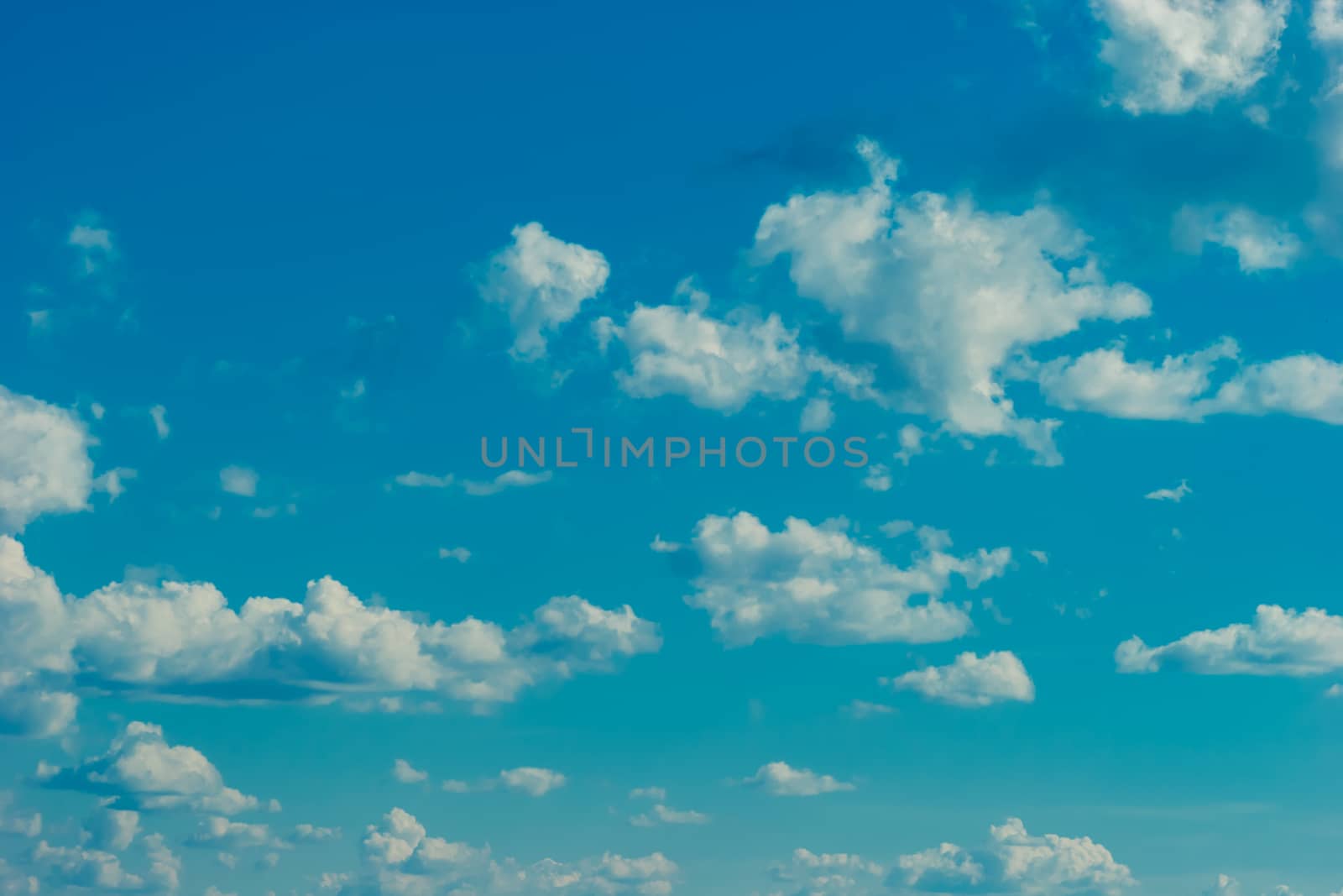 Deep blue bright sky with white fluffy clouds