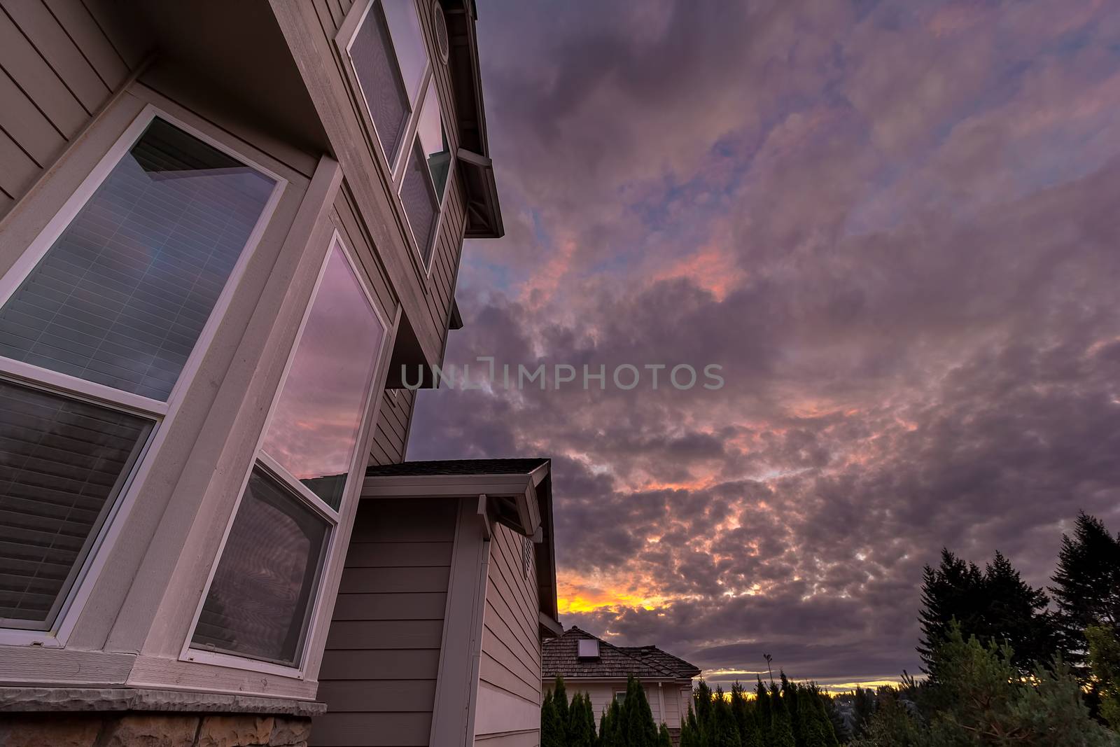 Reflection of sunset sky on windows of suburban neighborhood home in North America