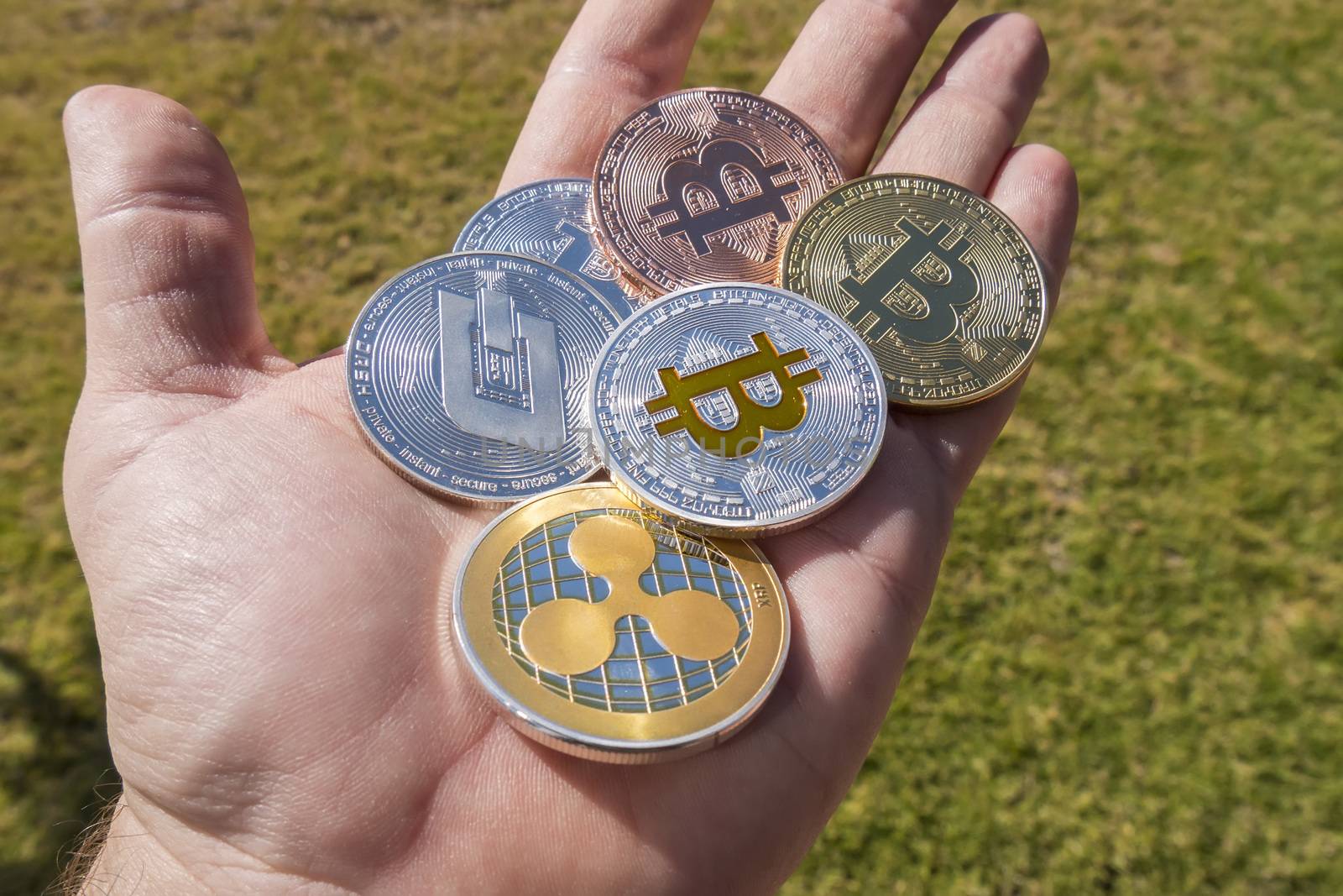 Cryptocurrency coins in a hand; Bitcoin, Ripple, Dash