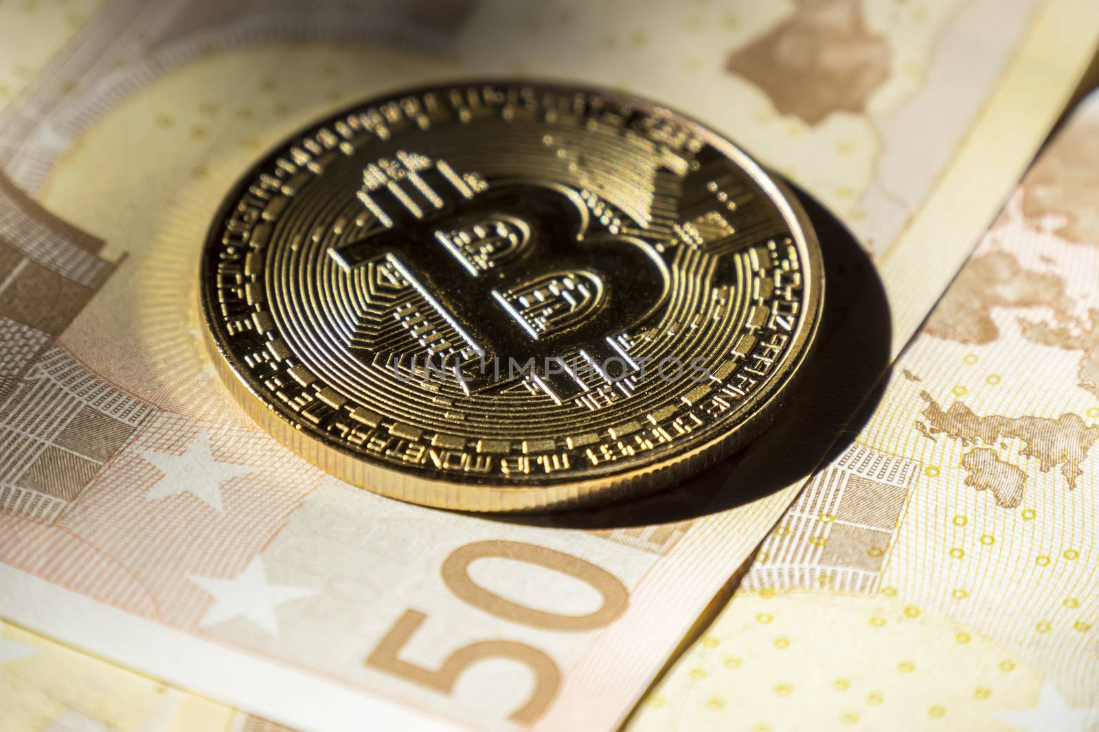 Cryptocurrency coins over euro banknotes; Bitcoin  coins