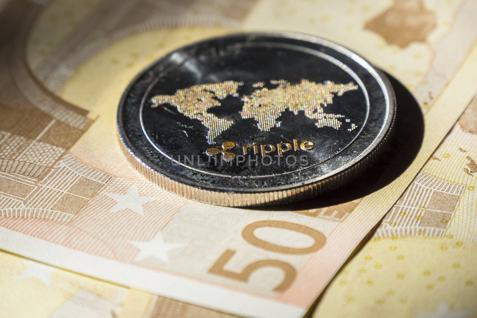 Cryptocurrency coins over euro banknotes; Ripple coin