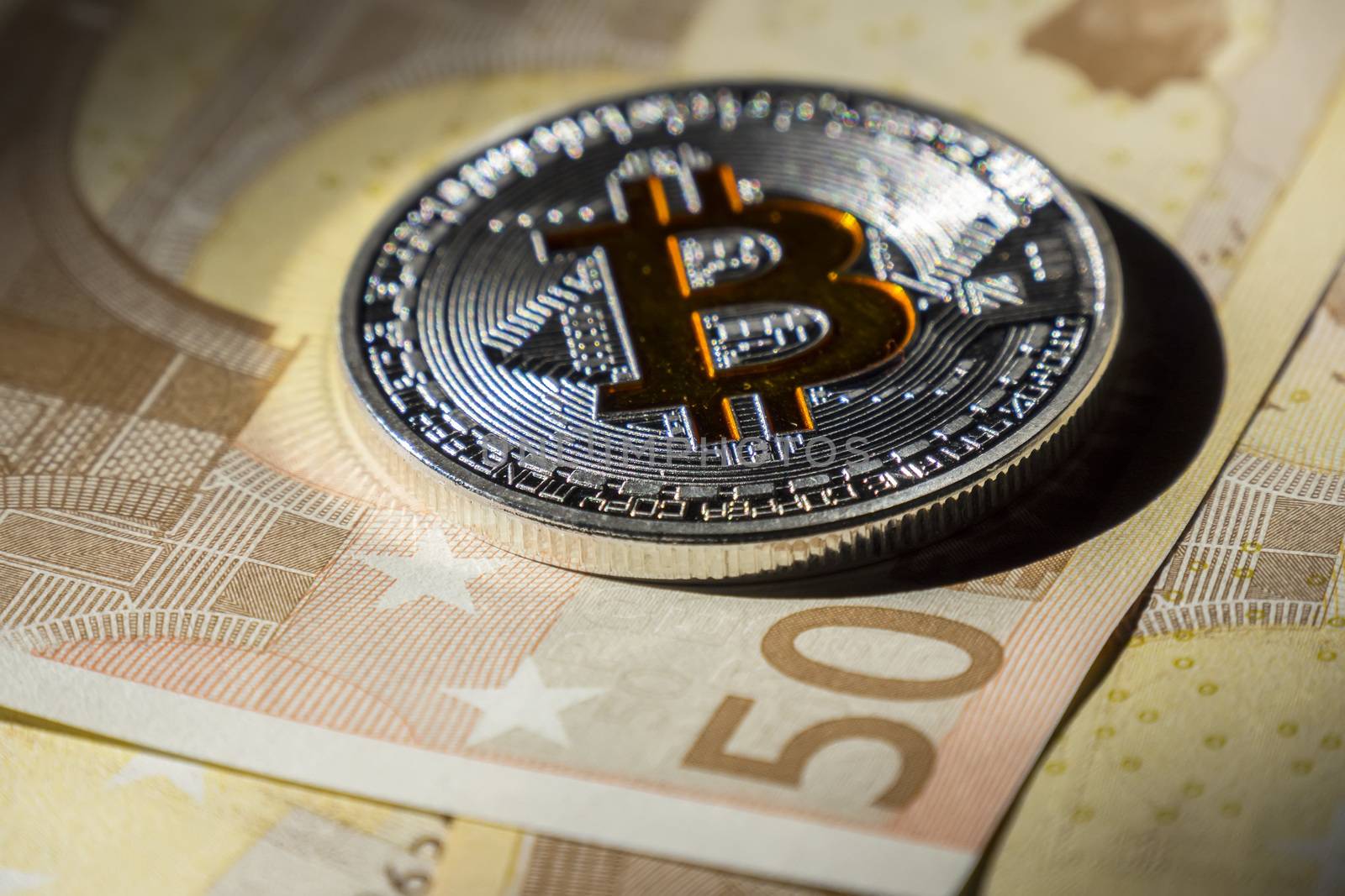Cryptocurrency coins over euro banknotes; Bitcoin  coin