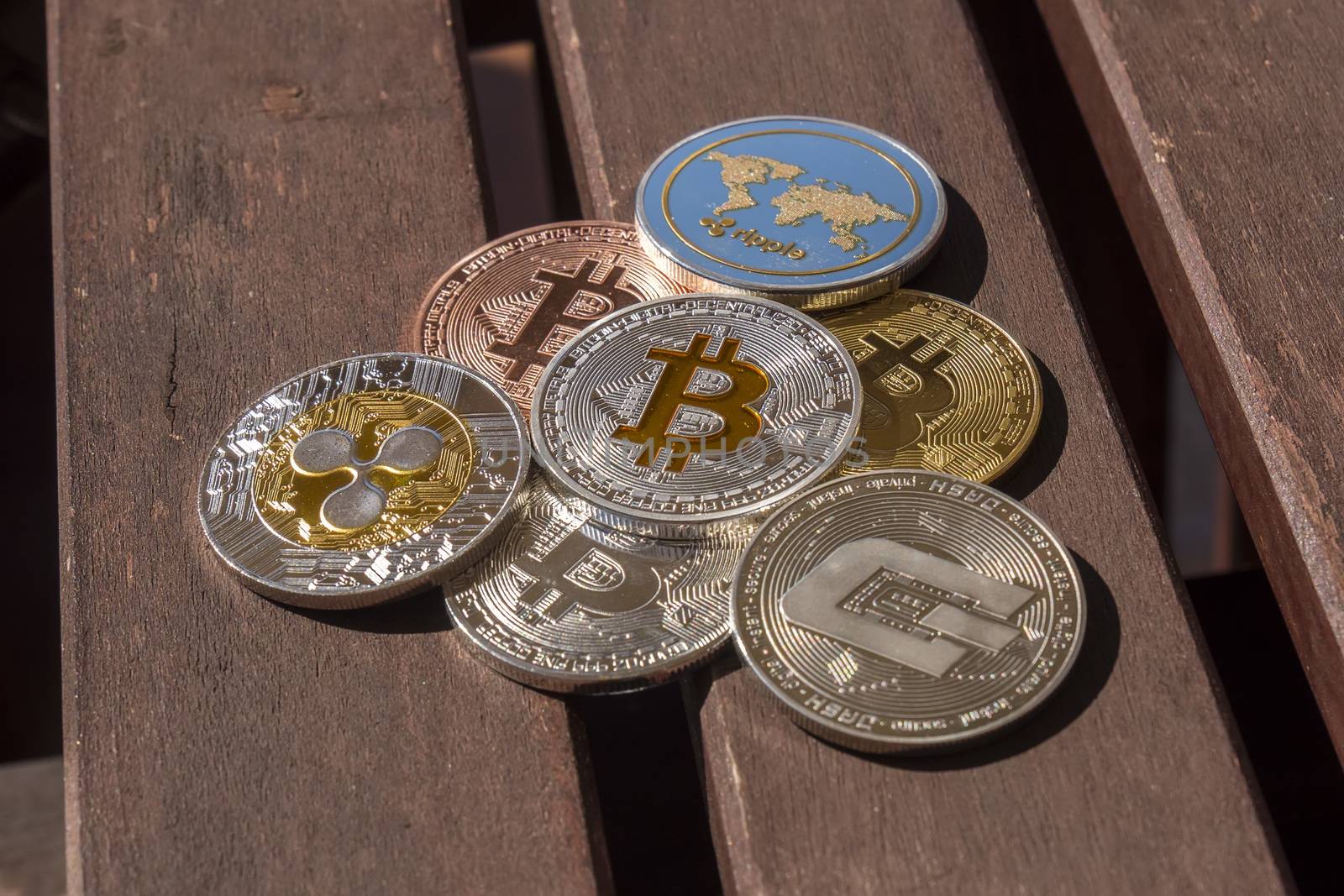 Cryptocurrency coins over a wood table; Bitcoin, Ripple, Dash