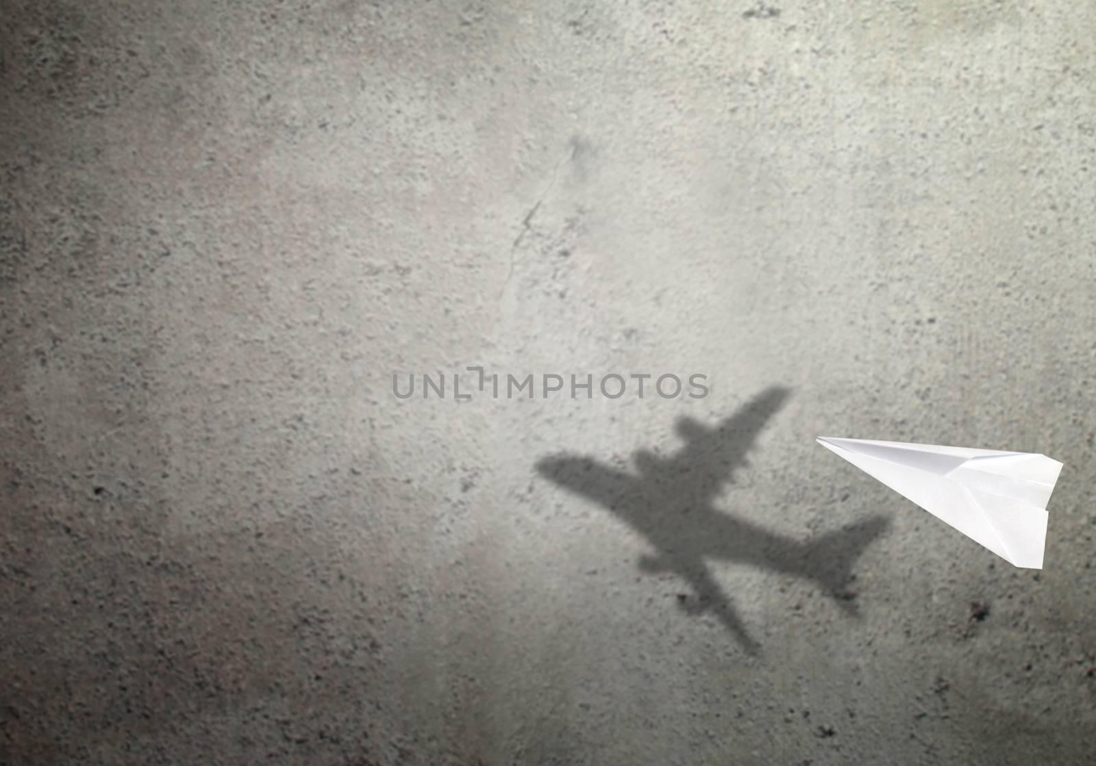 Paper plane in mid flight with shadow of a real plane