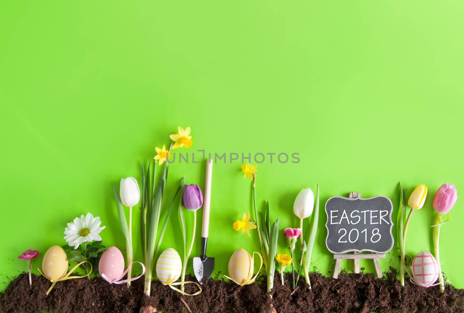 Easter flower bed garden background with row of painted eggs amongst flowers