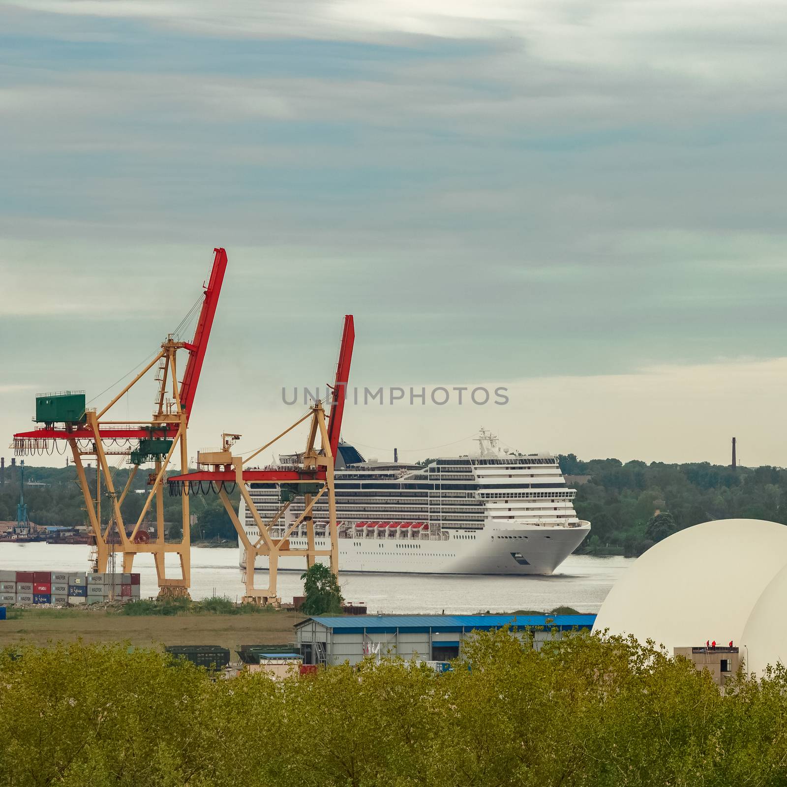 Big white cruise liner sailing past the cargo port