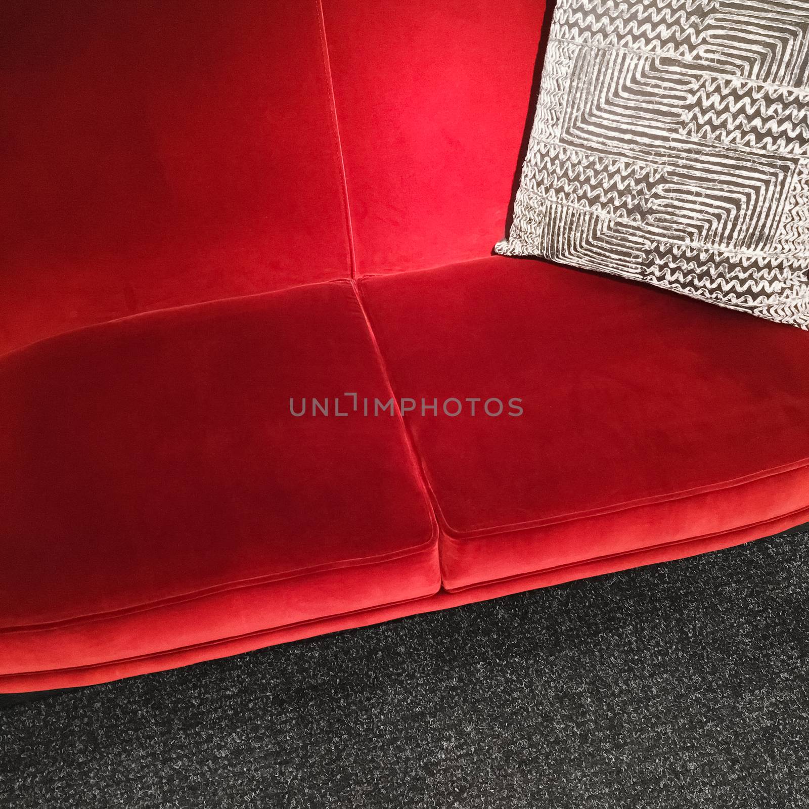 Red velvet sofa with gray ornamental cushion. Luxurious furniture.