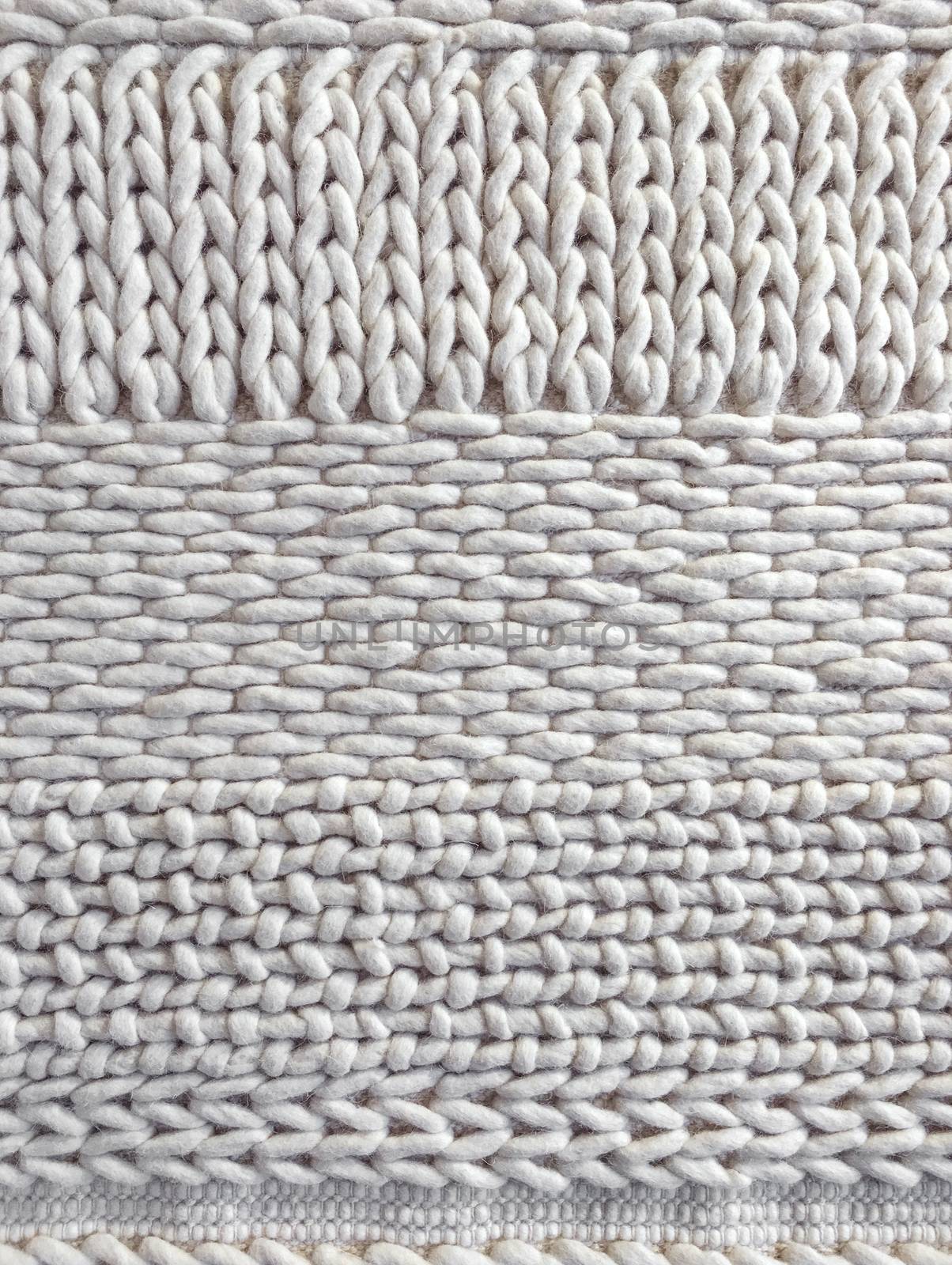 White wool knitted background with simple ornament. Handcrafted material.