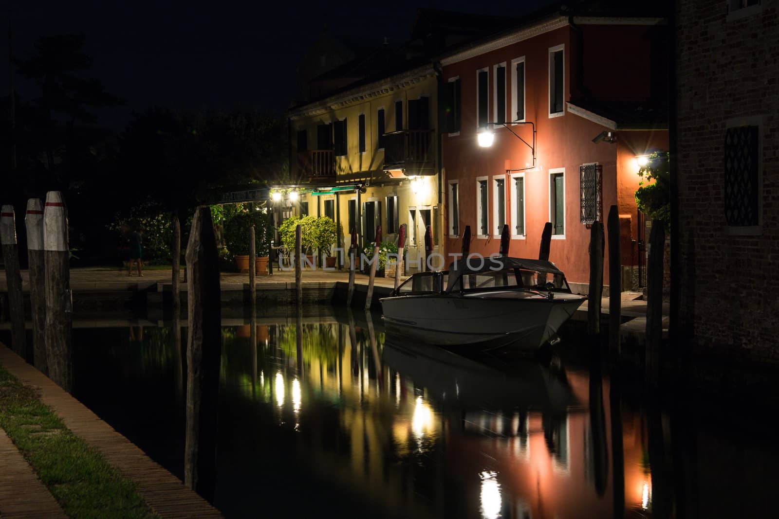 Beautiful quiet evening cityscape of Burano island in Venice. Colored buildings are illuminated by street lights reflected in a water canal. Boats are parked there. by MSharova