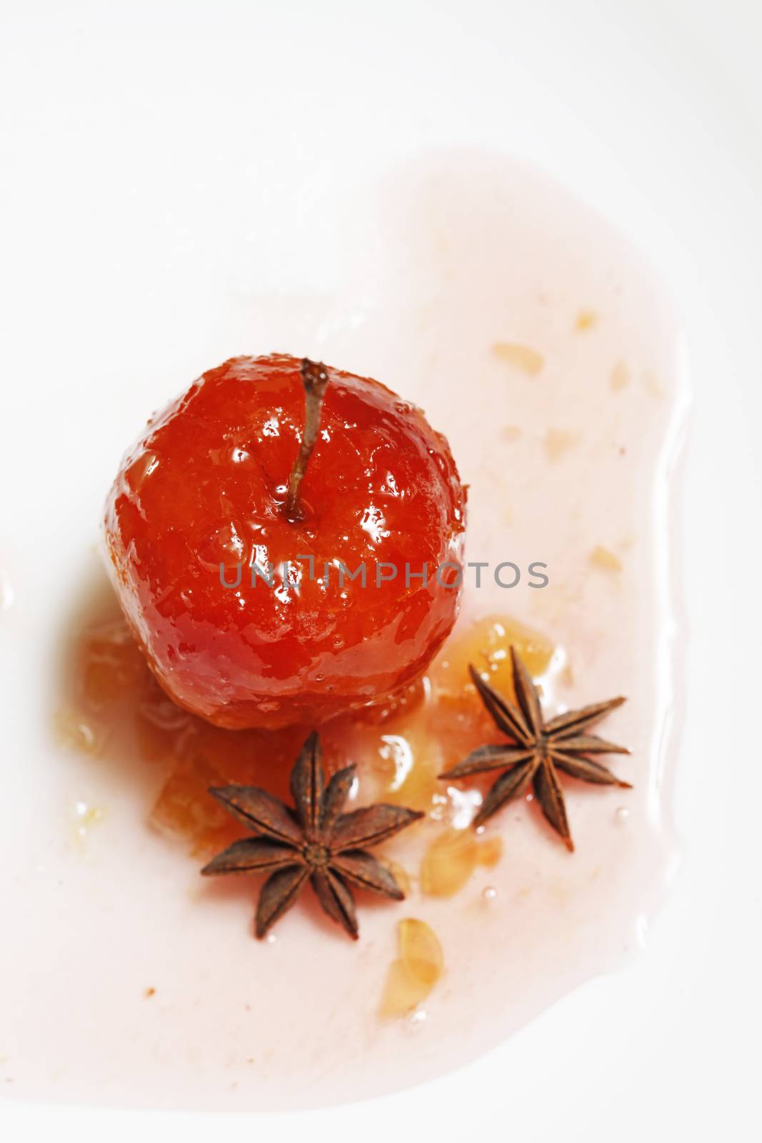Red apple in rose syrup with small pieces of zucchini and with anise over isolated white background