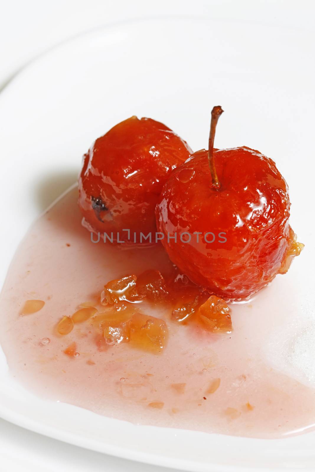 Red apple in rose syrup with small pieces of zucchini over isolated white background