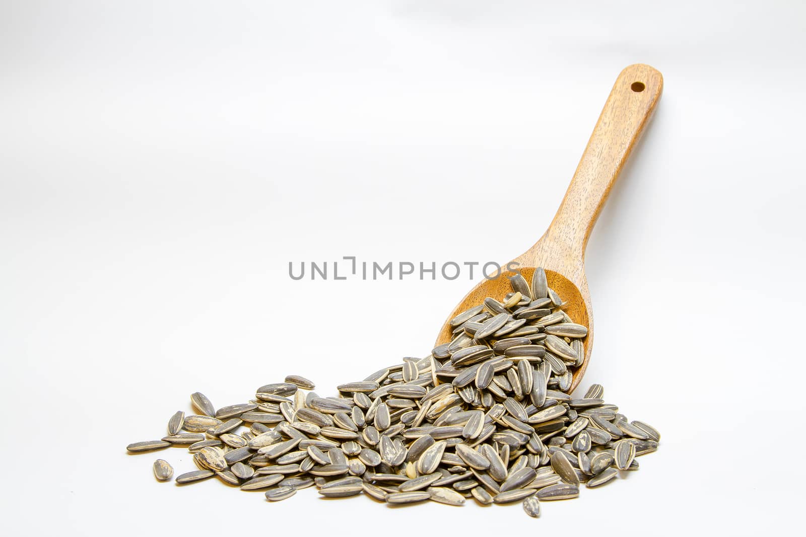 Dried sunflower seeds in the wooden spoon on white background.