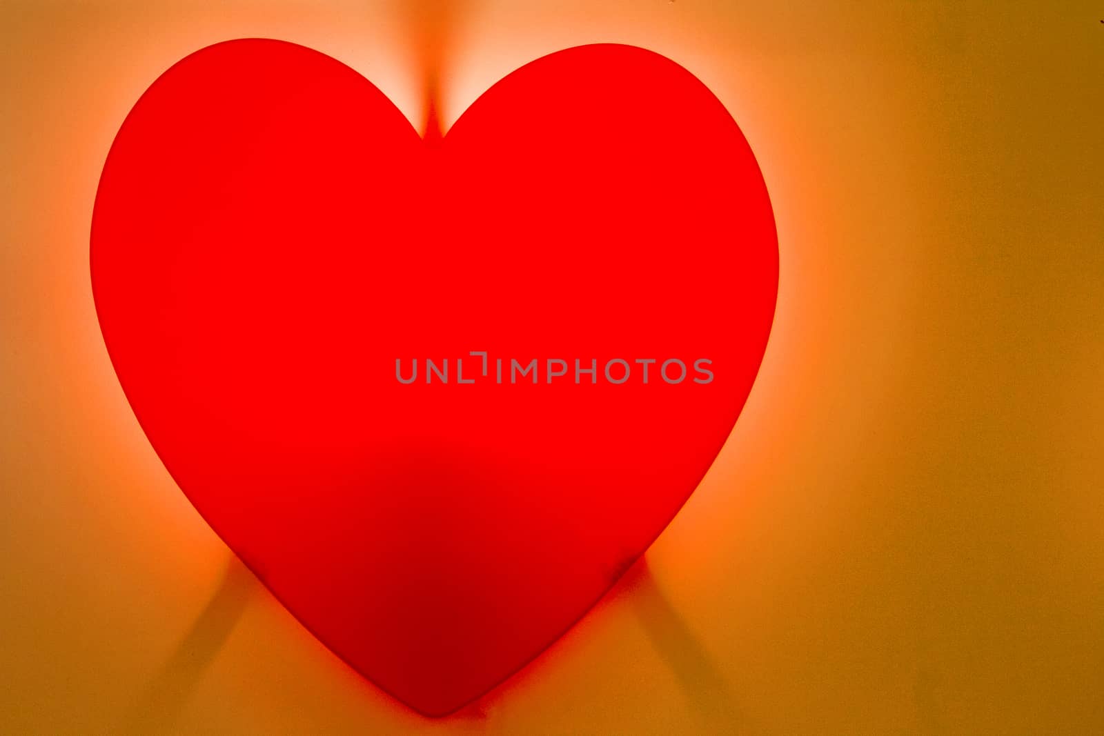 Red heart-shaped fire on red background on orange