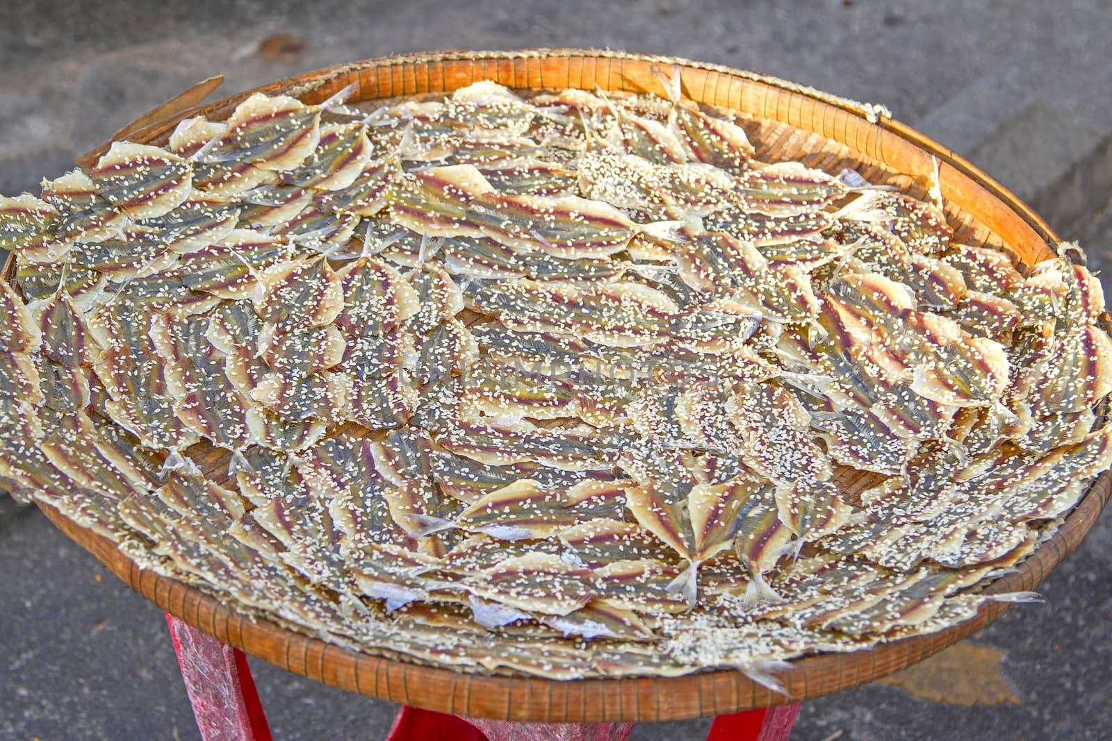 Dried fish sprinkle white sesame on a sieve.