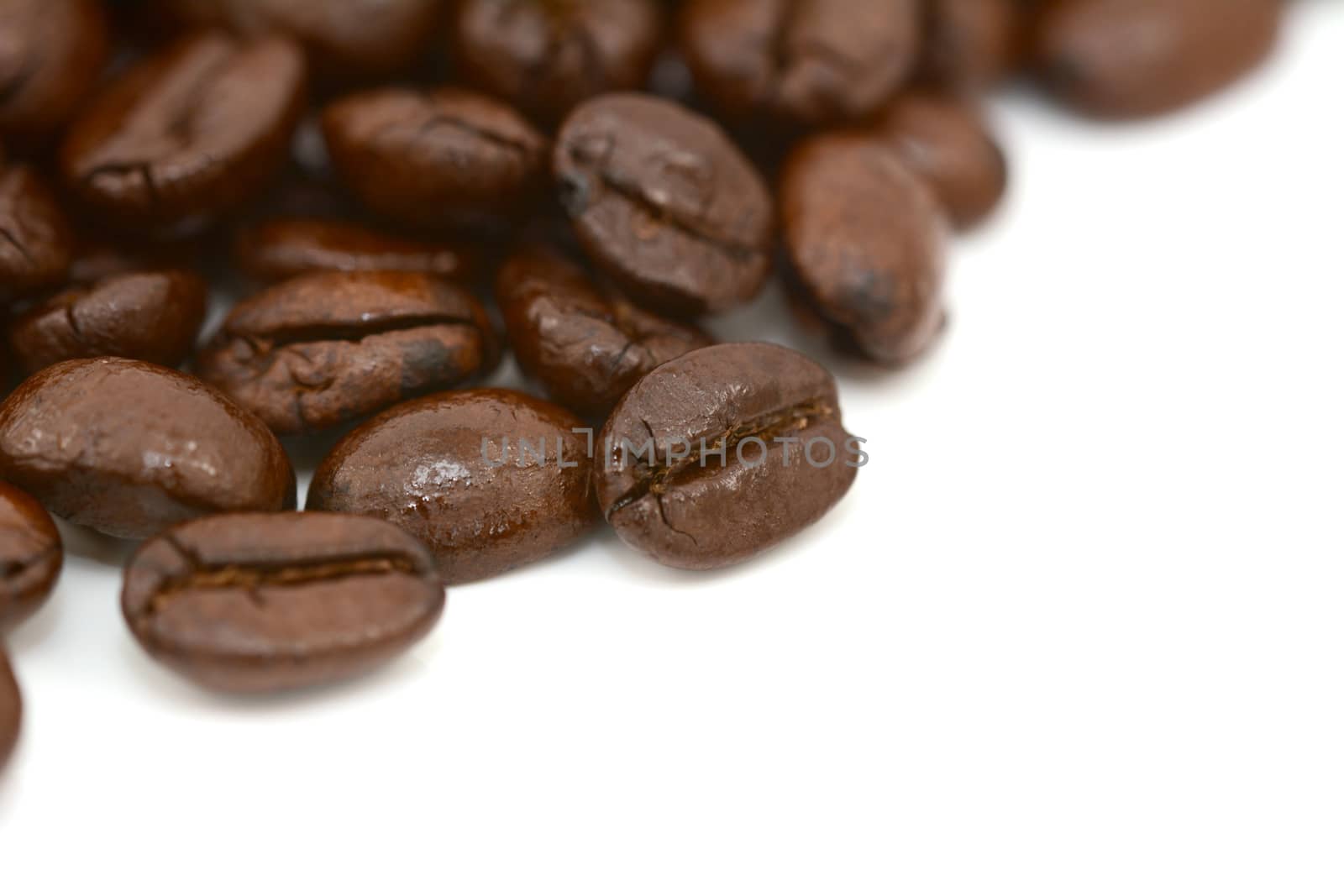 Close-up of roasted coffee beans in selective focus, on a white background
