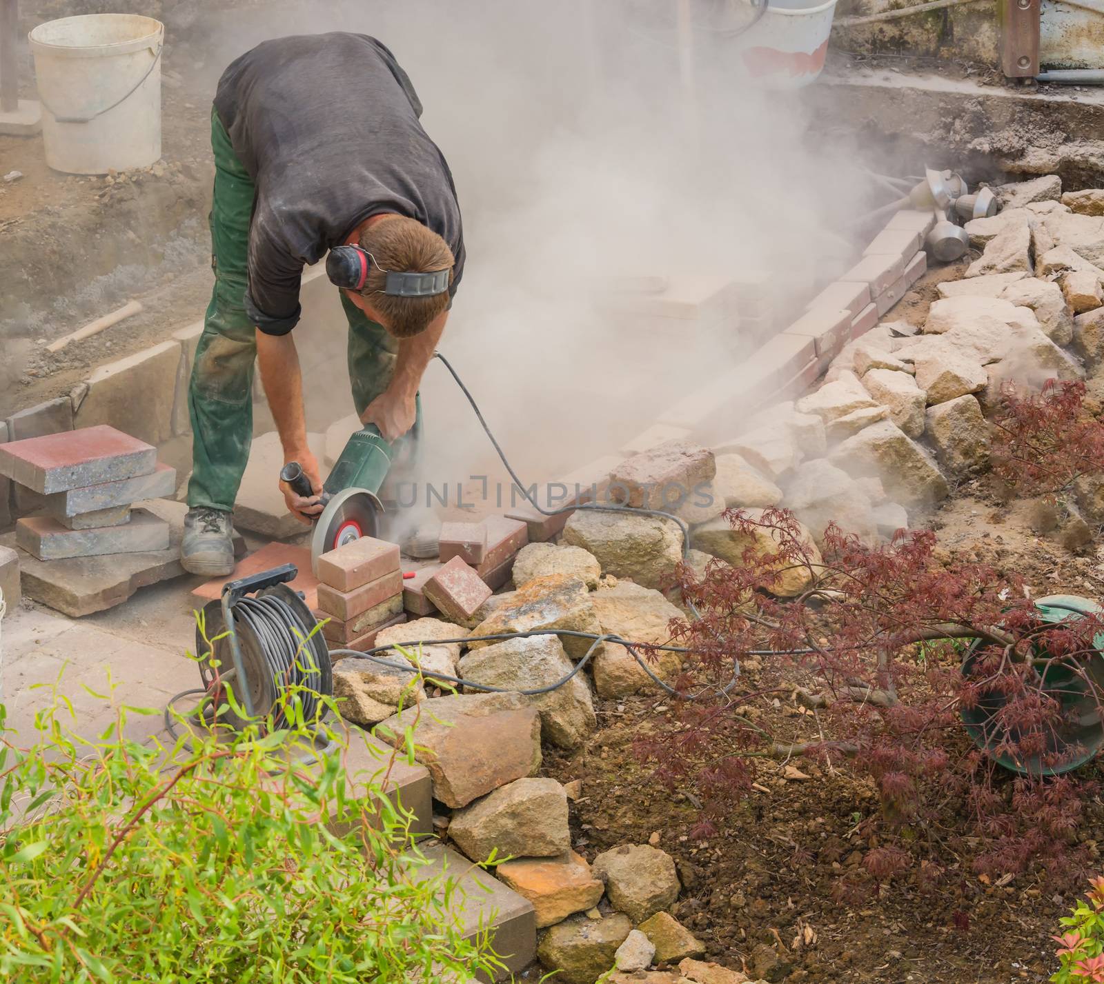 Man cutting stone slabs, concrete slab with an electric grinder