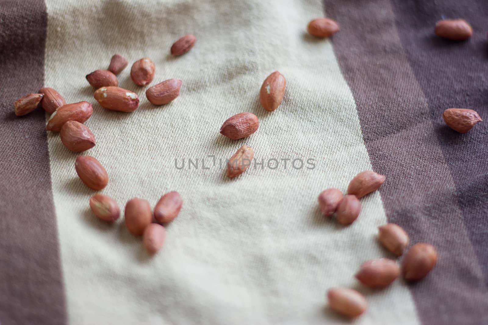 Peanuts in a peel on a brown fabric