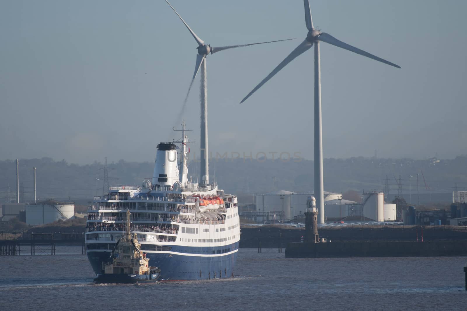 A passenger cruise liner passes two electricity generating wind turbines