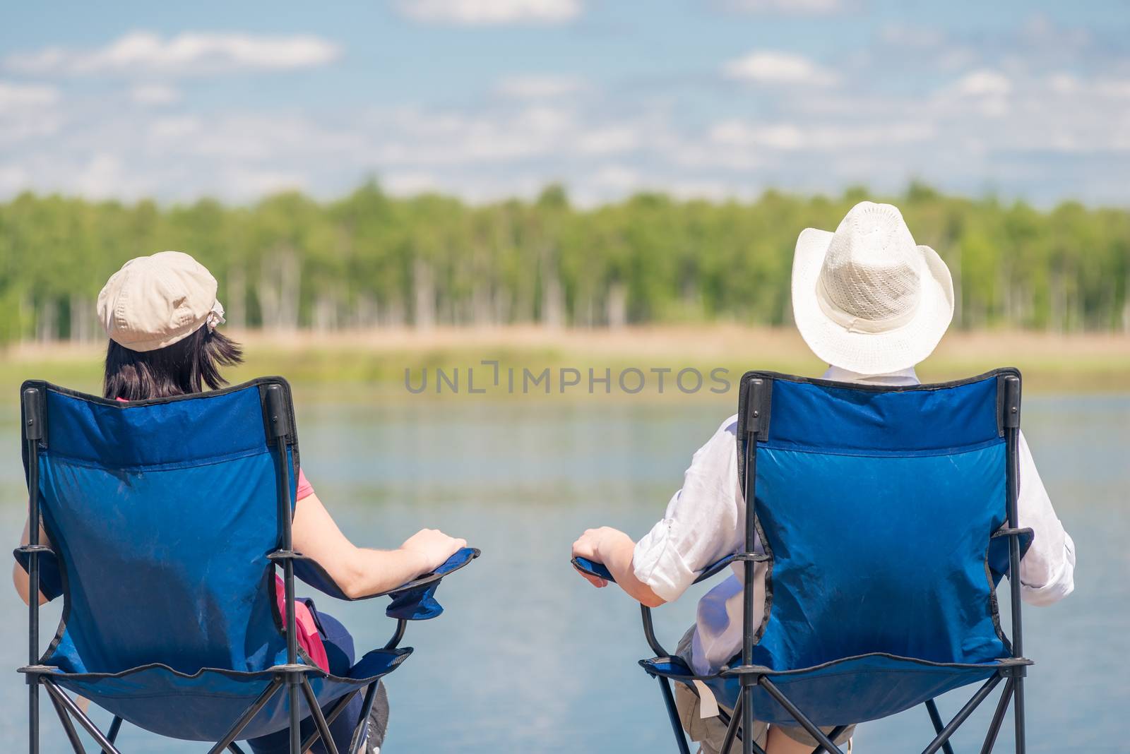 a loving couple sitting on chairs near a beautiful lake on a pie by kosmsos111