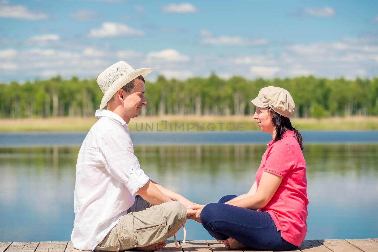 woman and man on a wooden pier near the lake resting