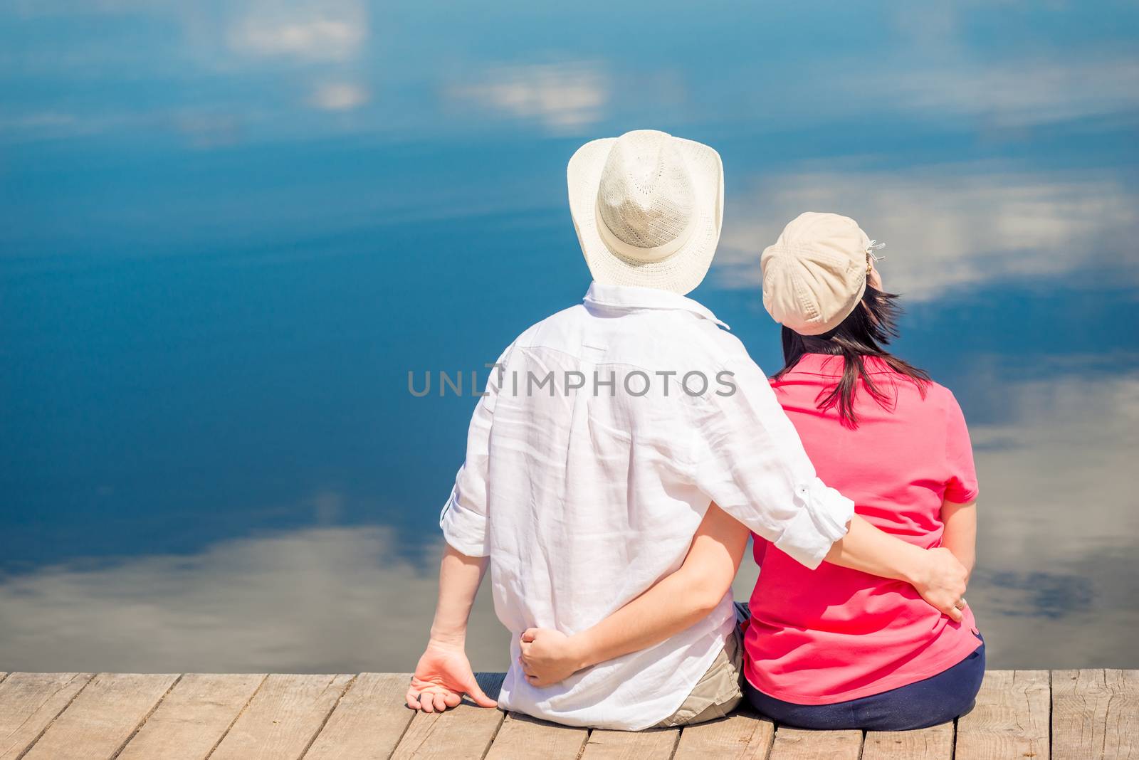loving couple hugs and enjoys relaxing near a beautiful lake, view from the back