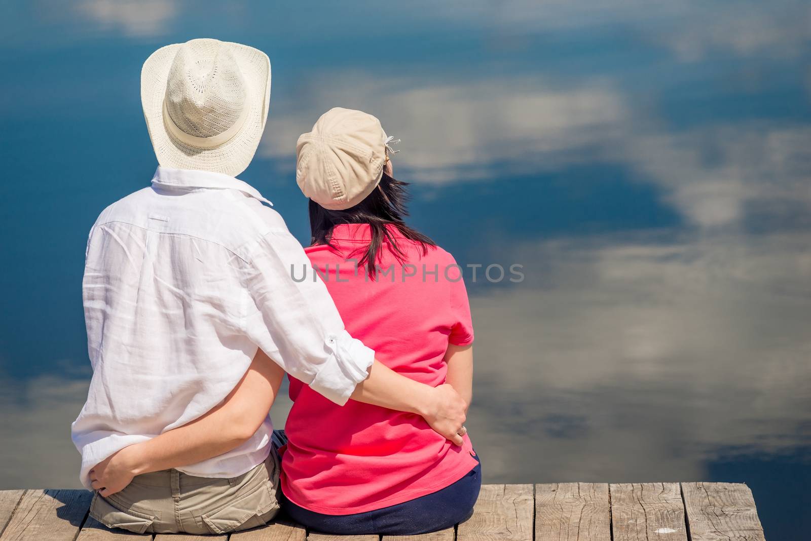 happy couple hugging and enjoying rest near beautiful lake, view from back