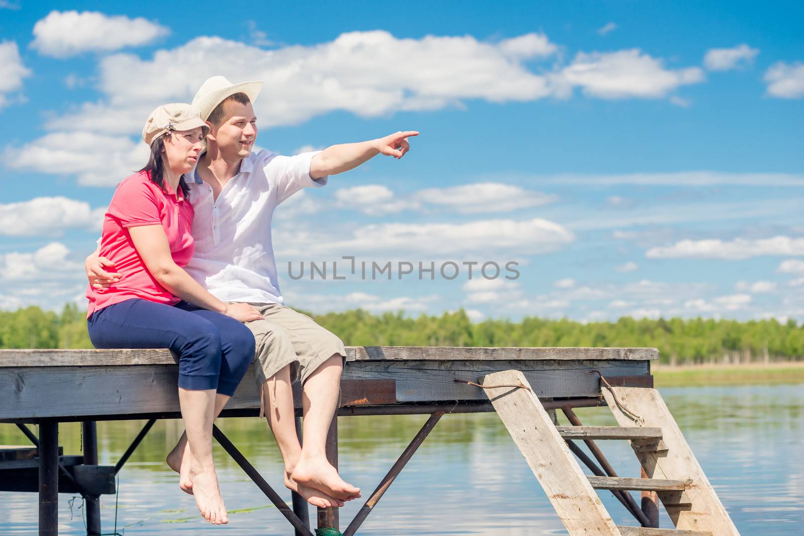 30-year-old couple resting on pier, man pointing at lake by kosmsos111