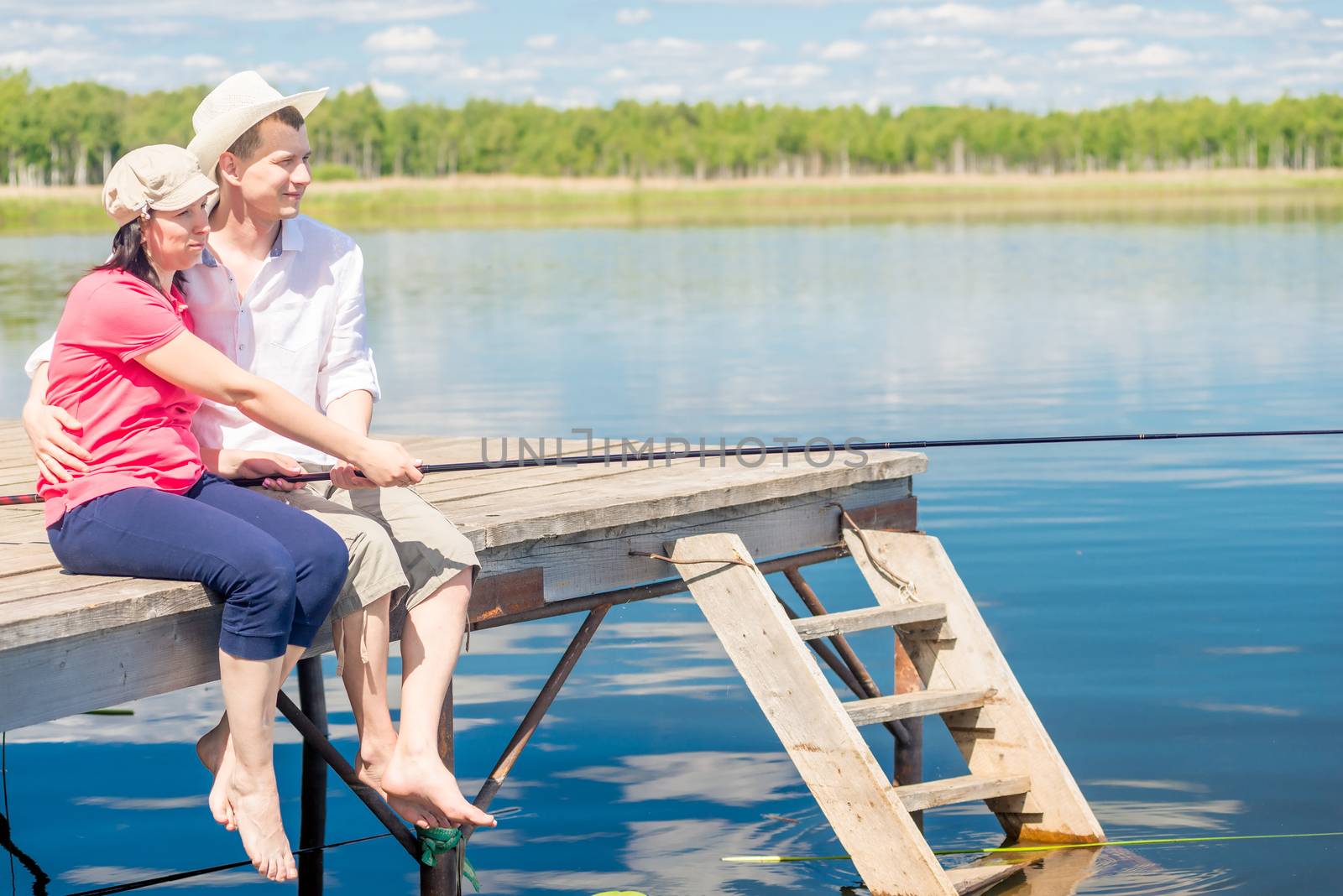 happy couple on the pier with bare feet catching fish on a beaut by kosmsos111