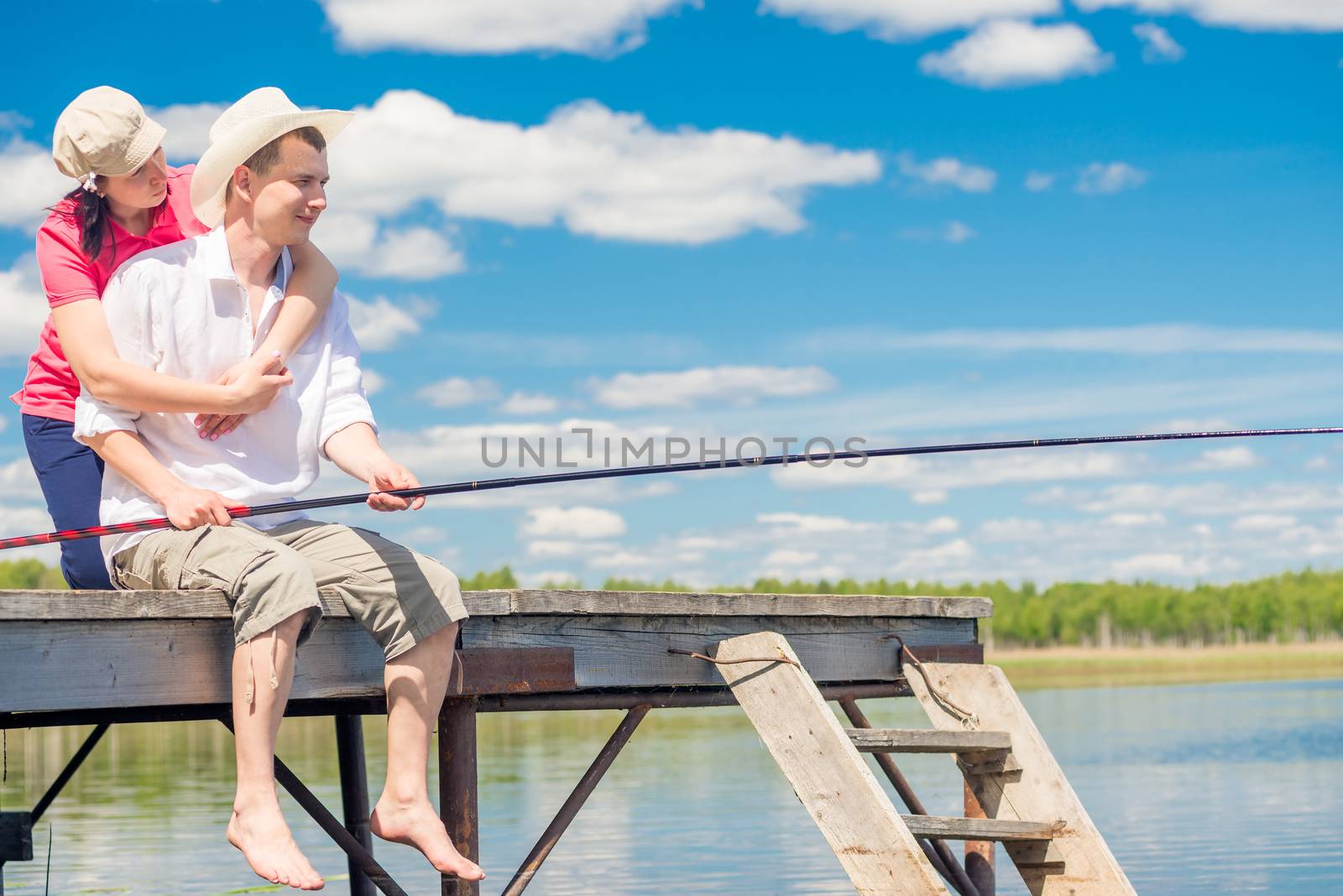 on a wooden pier, a loving couple with a fishing rod is fishing by kosmsos111