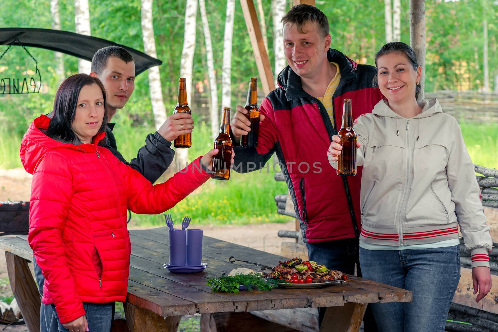 friends with a barbecue and beer on the nature in the gazebo