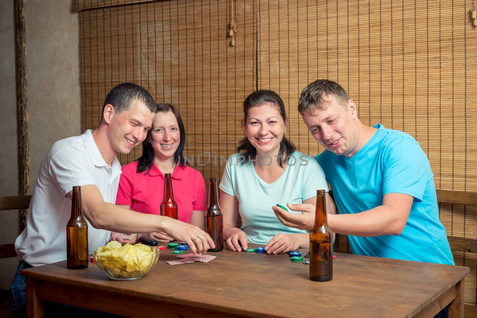 happy four friends while playing poker at the table