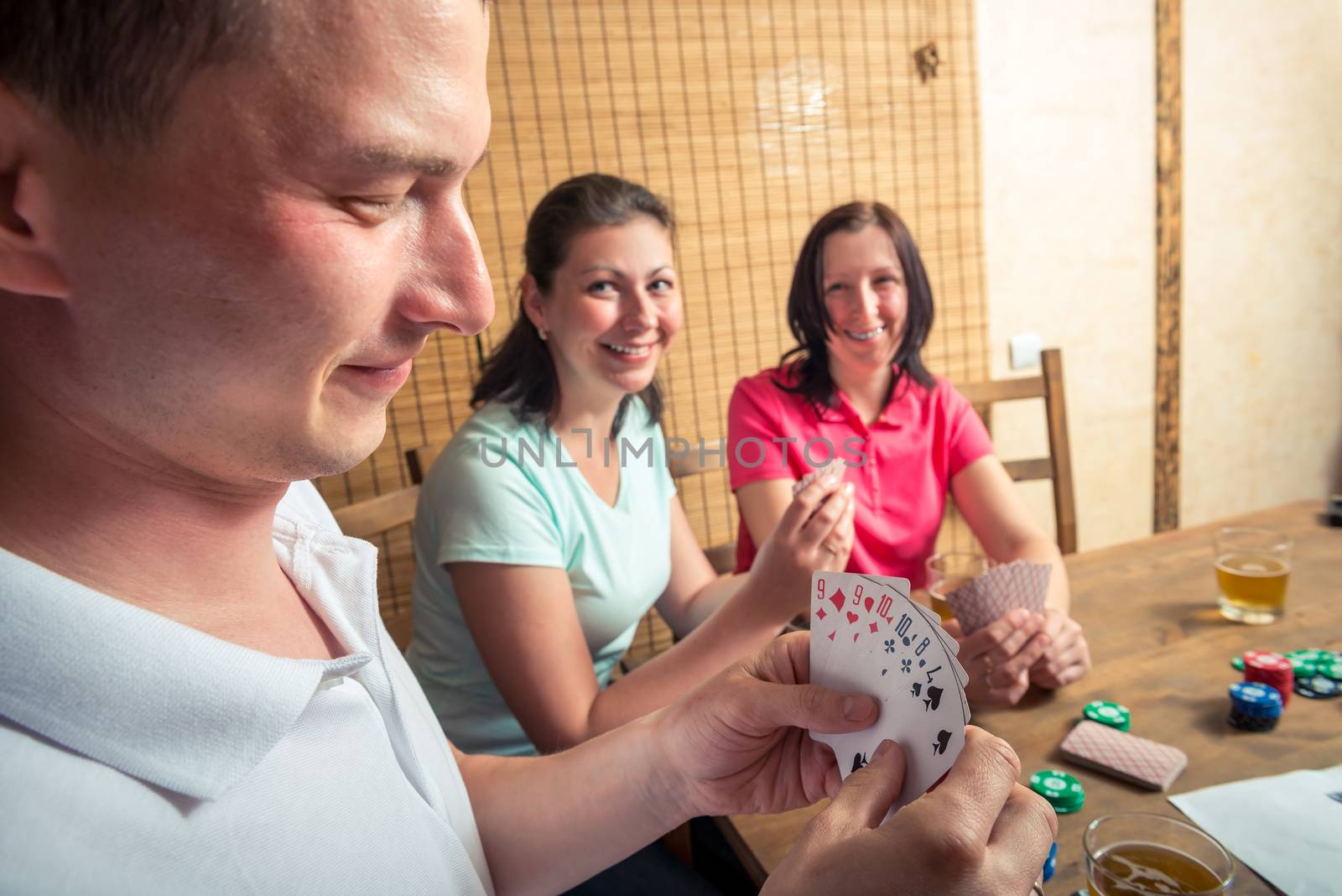 man and two women playing poker, man showing his cards