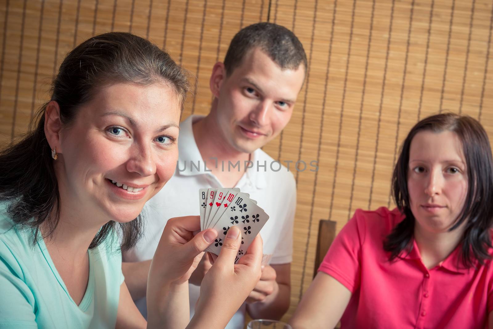 happy man and two women playing poker, a woman showing their cards