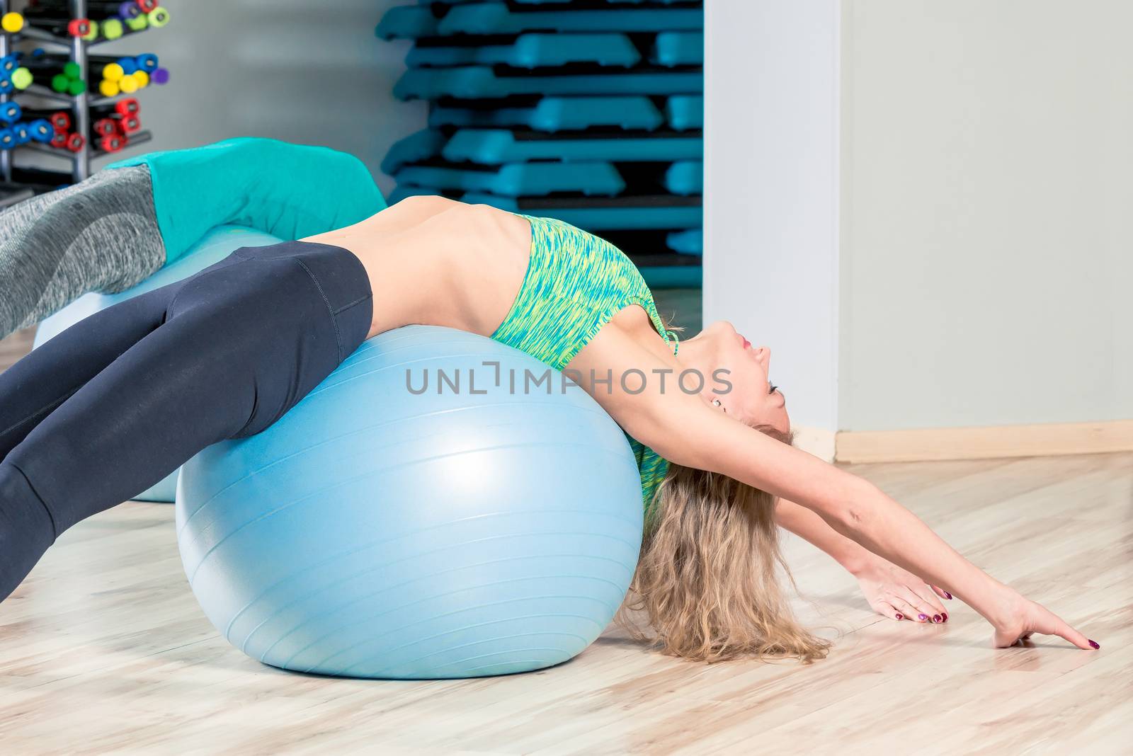 slender woman stretches muscles, classes in a group with gymnastic balls in the gym