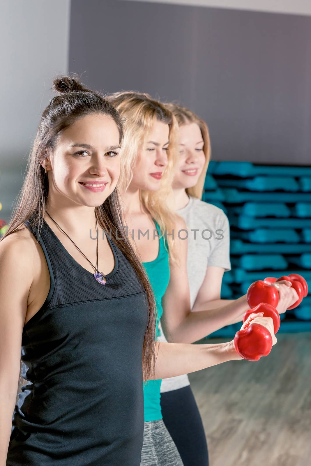 horizontal close-up portrait of three girls in training with dumbbells