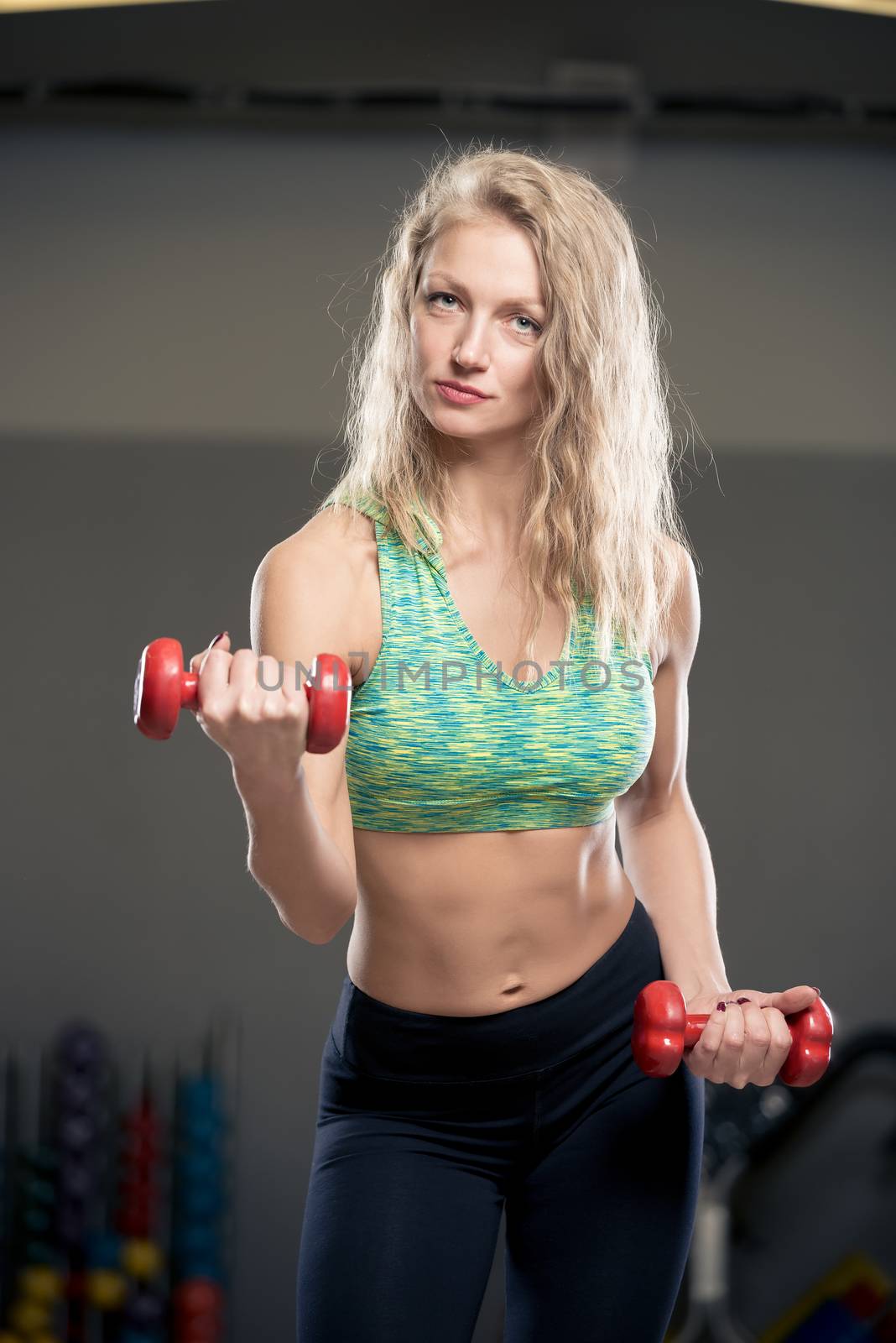 portrait of a trainer with dumbbells during a workout in the gym by kosmsos111