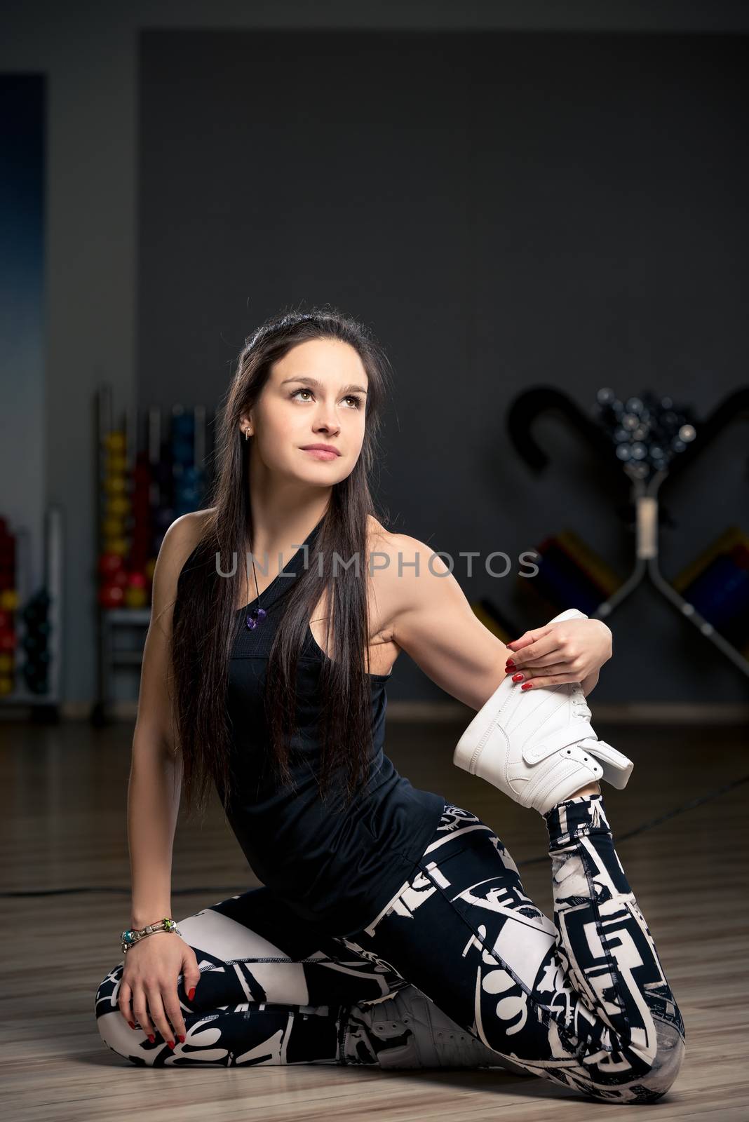 young woman in the gym on the floor doing stretching exercises by kosmsos111