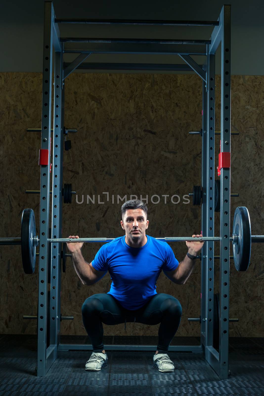 strong young bodybuilder with a barbell in the gym is practicing