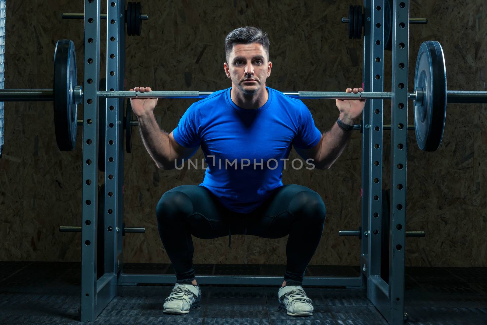 cute young bodybuilder with a barbell in the gym is practicing