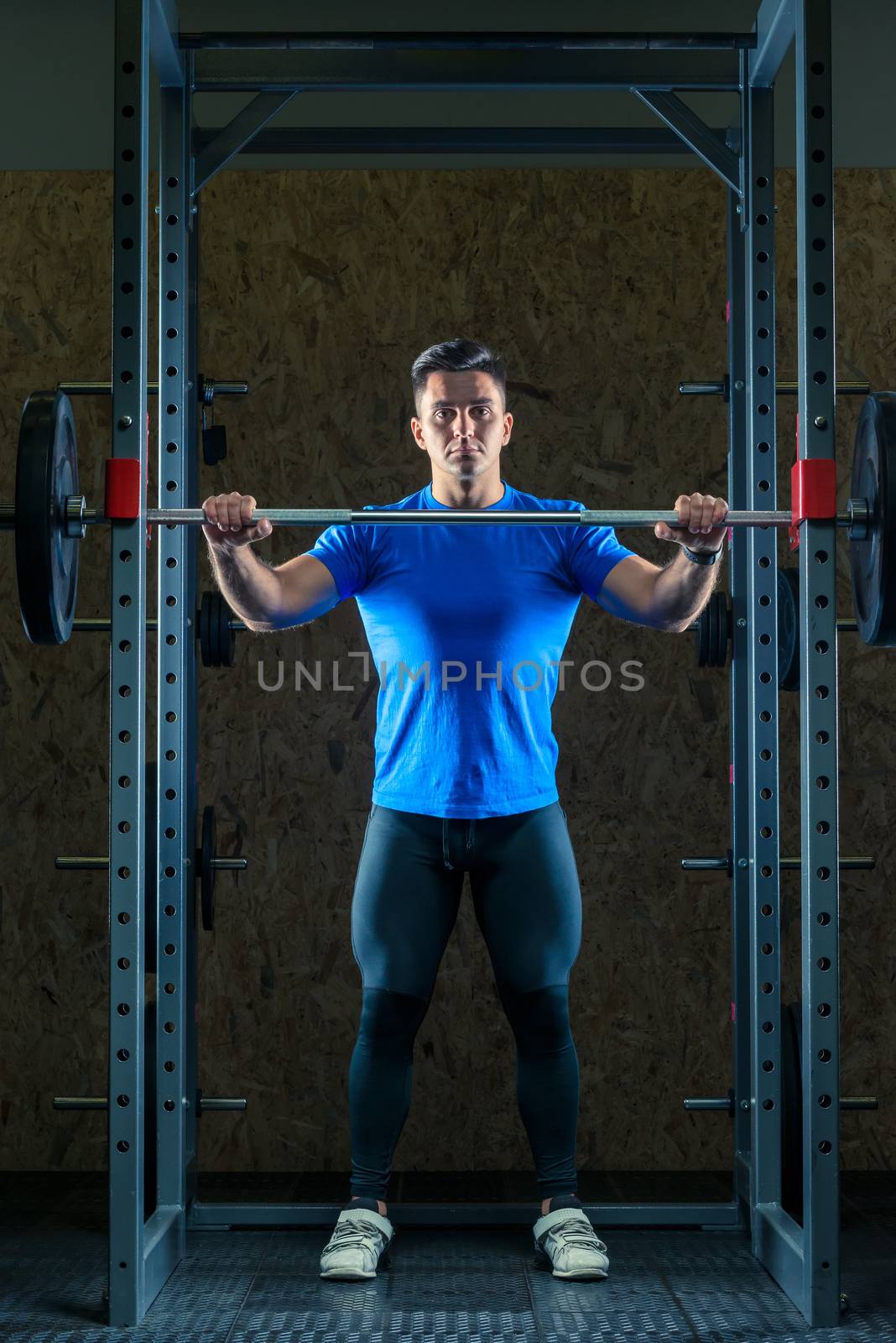 portrait of a young strong athlete at the gym in the gym with a by kosmsos111