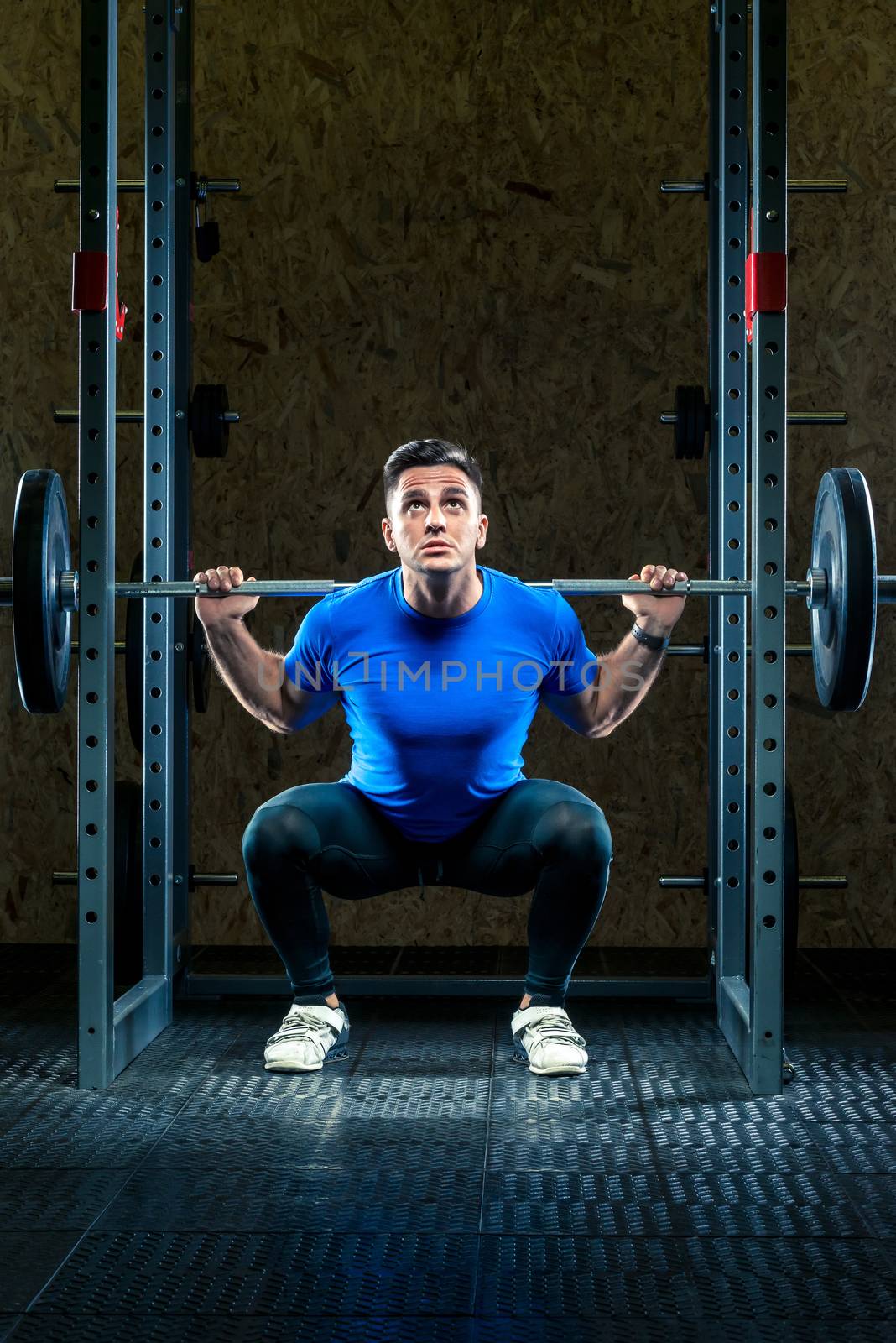 athlete bodybuilder prepares to lift a heavy bar in the gym