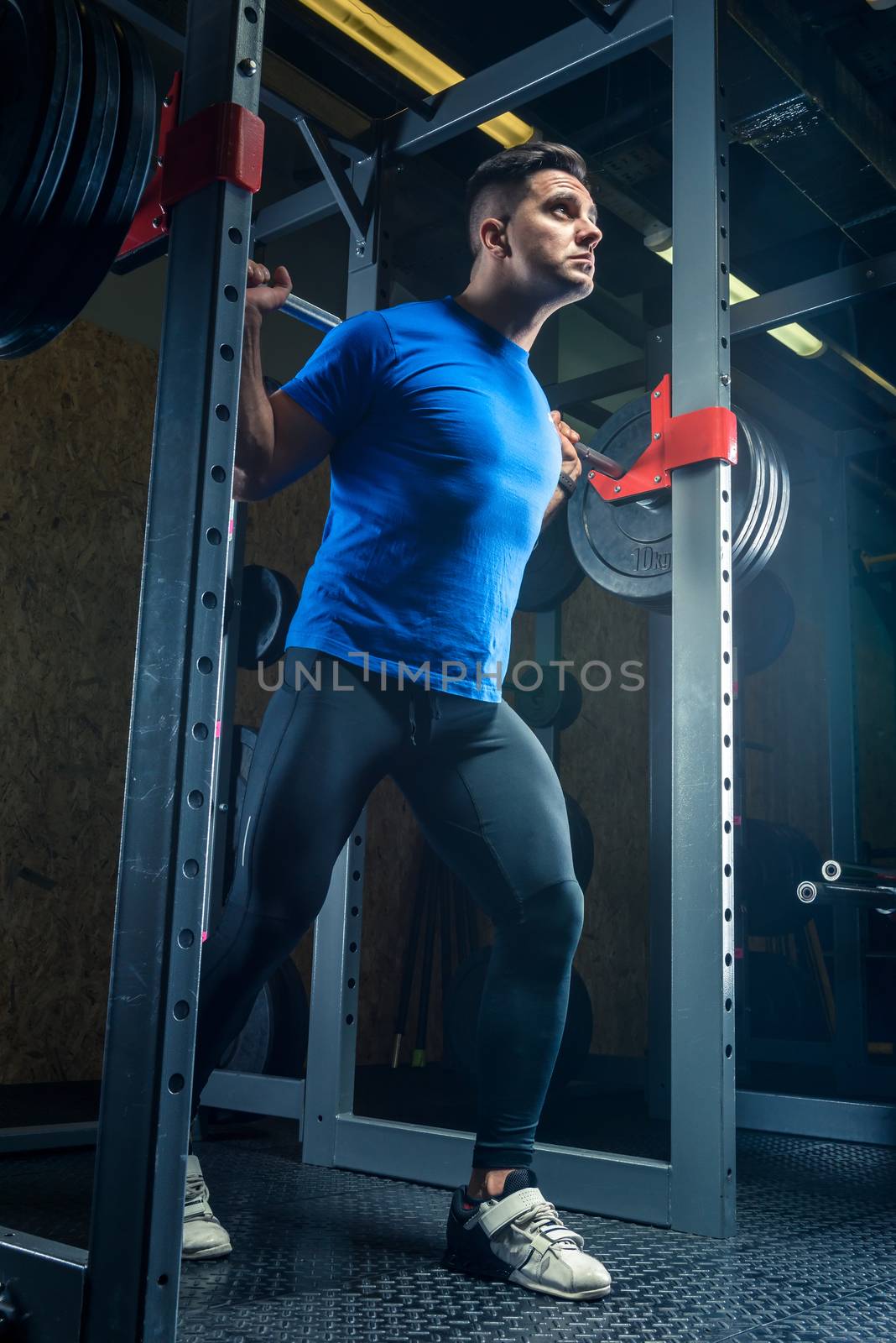 portrait of a bodybuilder with a barbell in the gym during training, bottom view