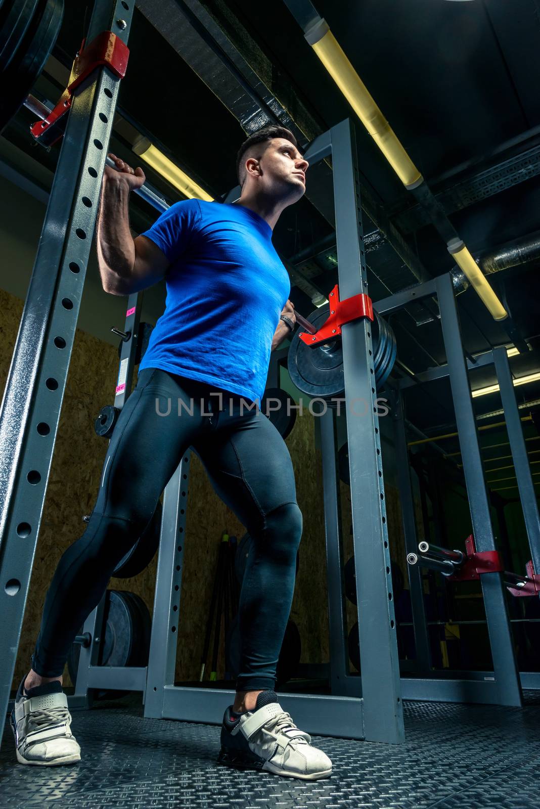 strong athlete in training in the gym, a man raises a heavy barbell