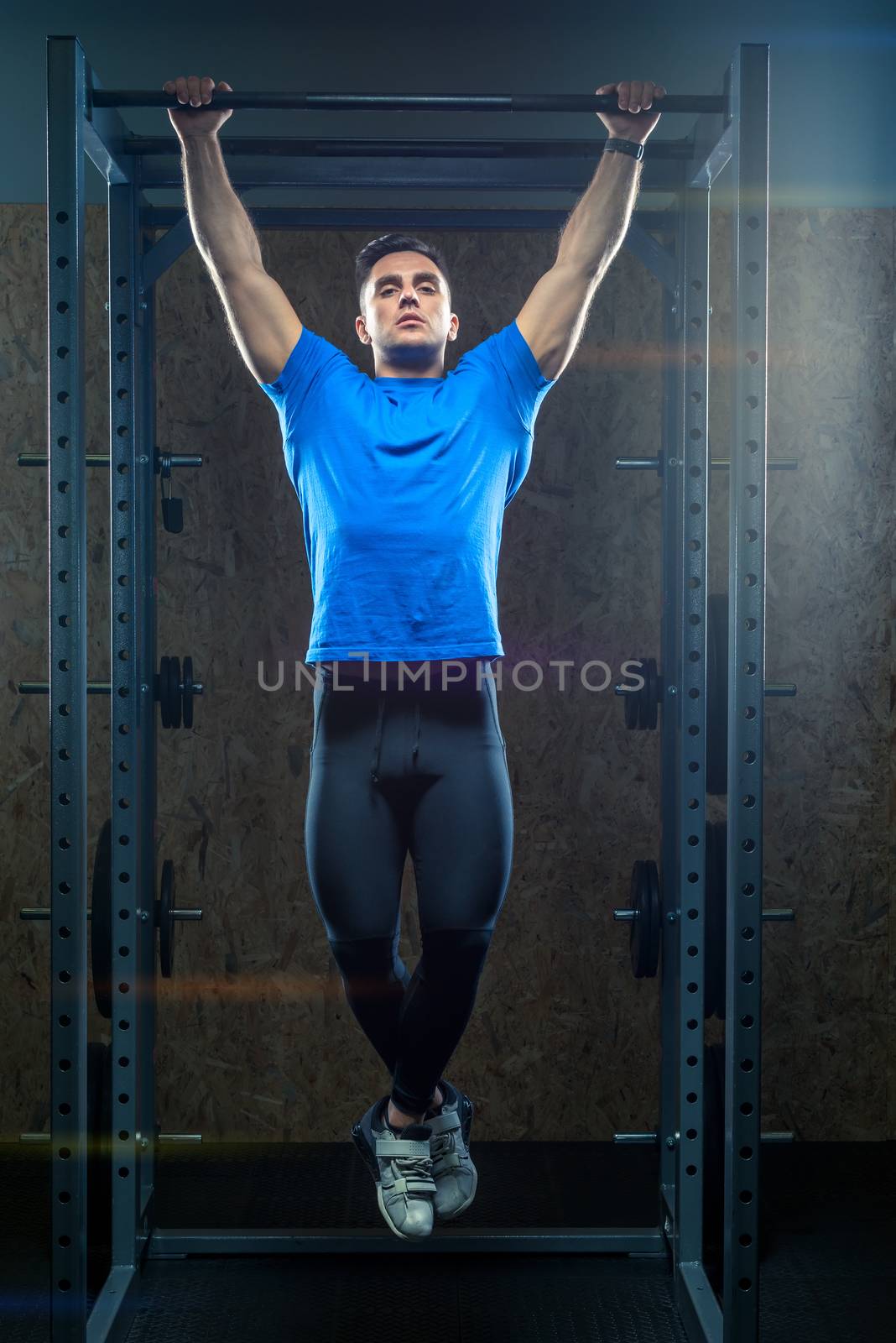 strong athlete in the gym in training, pulls up on the bar by kosmsos111