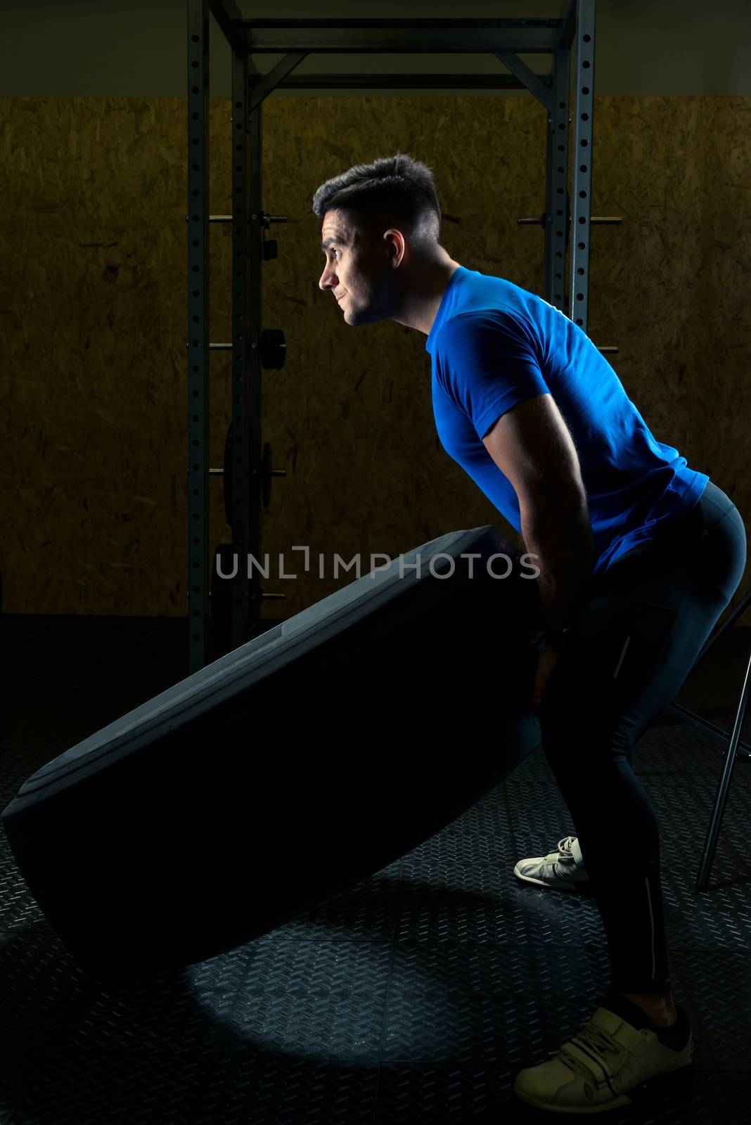 bodybuilder lifts a heavy wheel in the gym