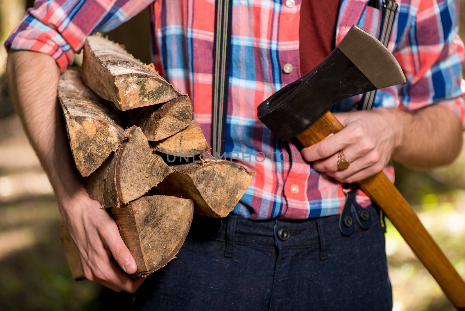 hands of a forester close-up with firewood and an ax