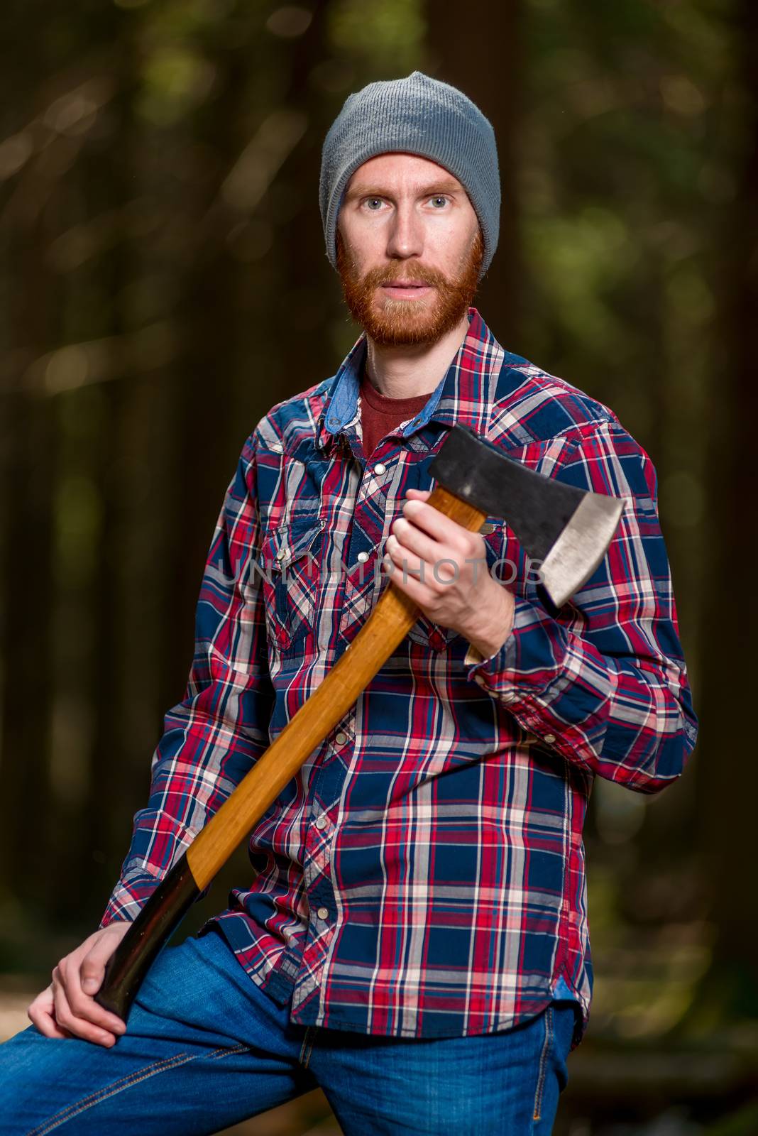 Bearded woodcutter with ax posing in forest